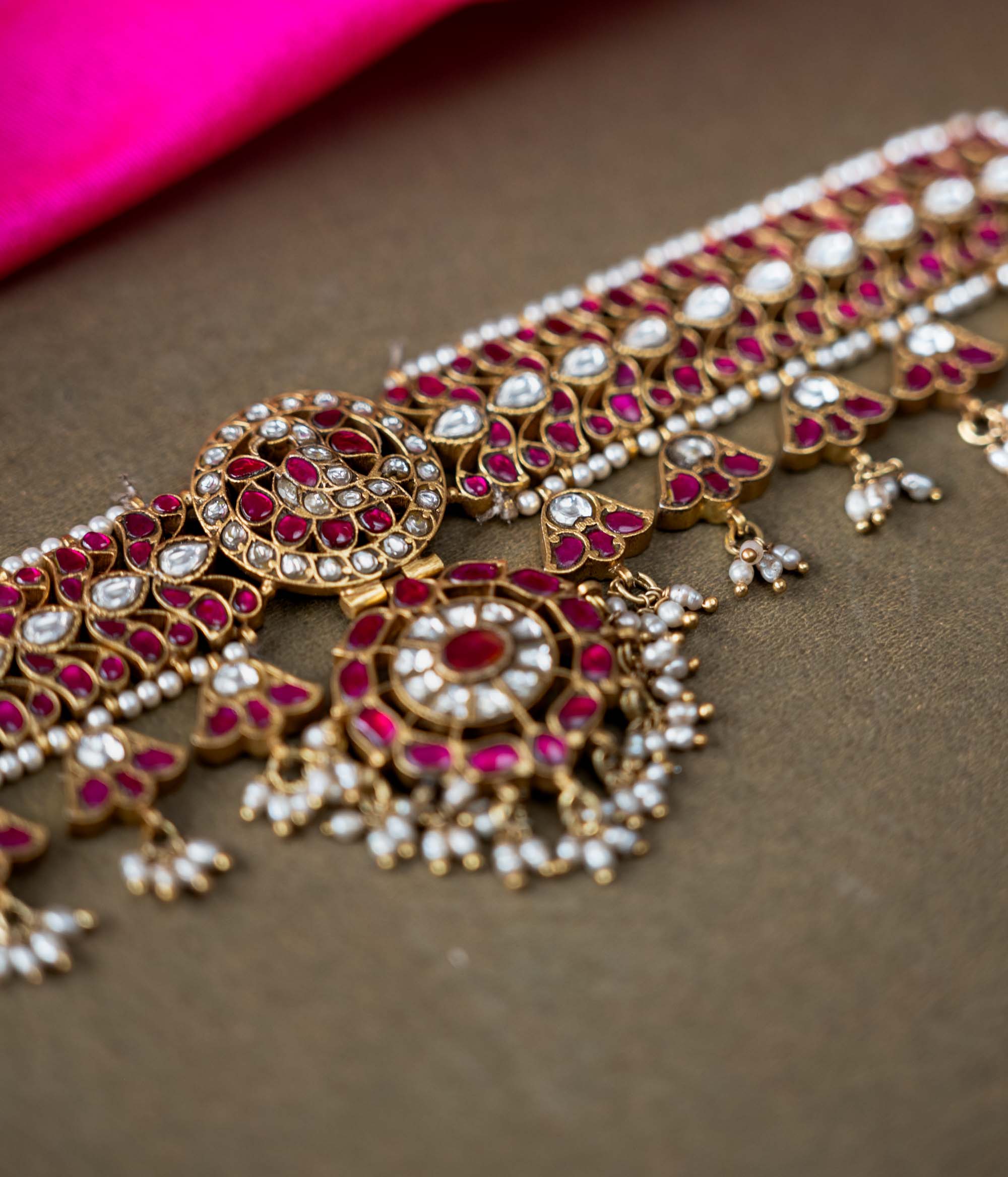 A 92.5 sterling silver choker, adorned with dazzling polki stones, red Kundan stones, and pearl droplets, embodying regal charm and timeless grace.