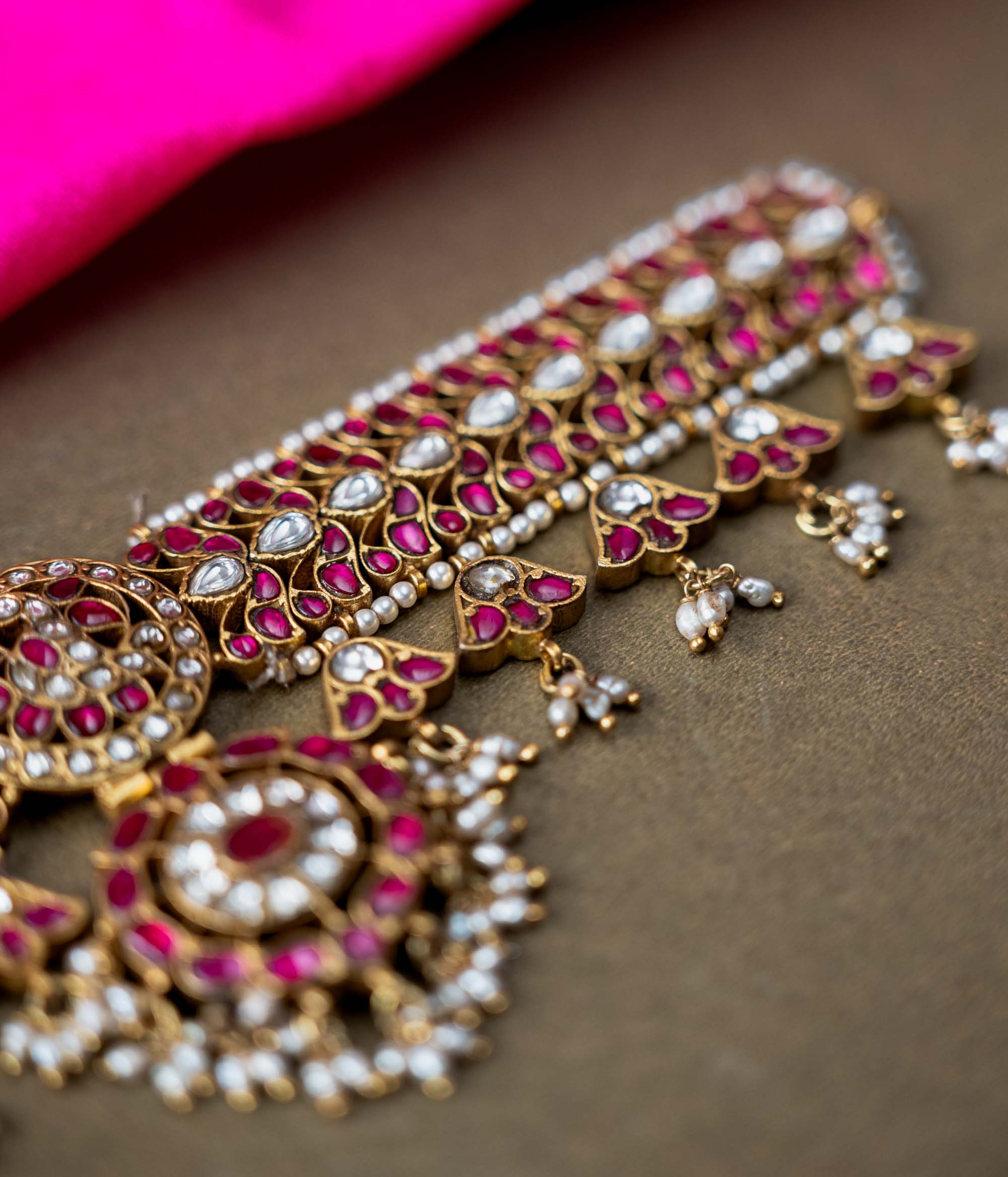 A 92.5 sterling silver choker, adorned with dazzling polki stones, red Kundan stones, and pearl droplets, embodying regal charm and timeless grace.