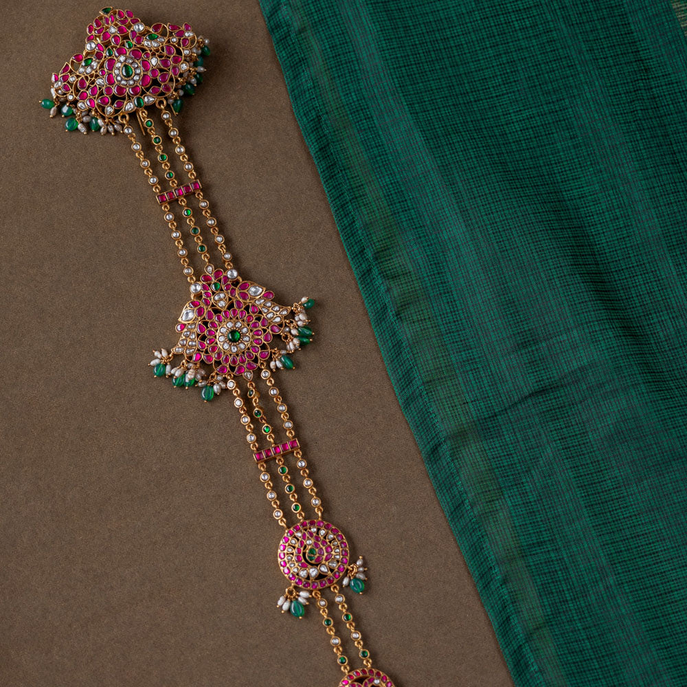 A handcrafted 92.5 sterling silver hair ornament (jadai) featuring red, green, and white Kundan stones, green beads, and pearls, adding a regal touch to bridal and traditional wear.