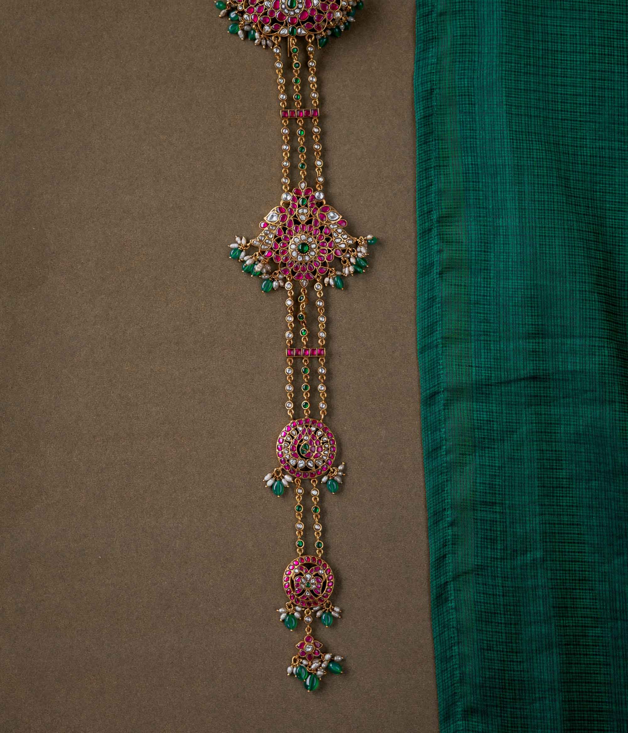 A handcrafted 92.5 sterling silver hair ornament (jadai) featuring red, green, and white Kundan stones, green beads, and pearls, adding a regal touch to bridal and traditional wear.