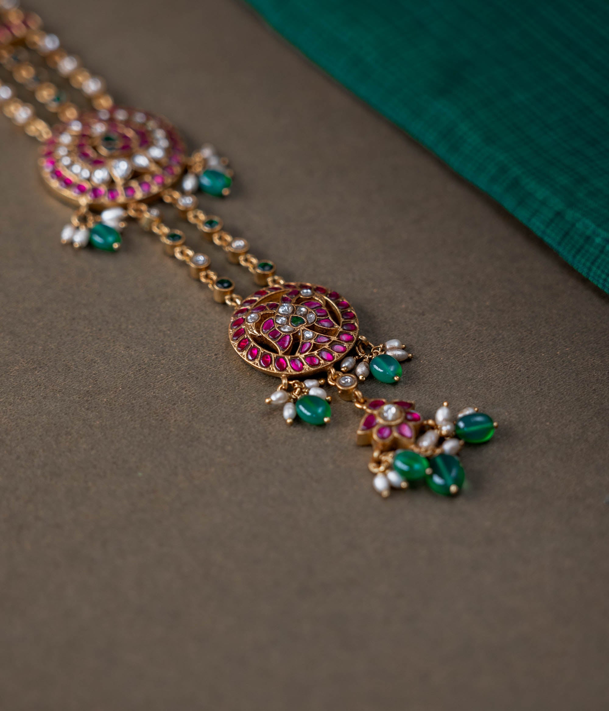 A handcrafted 92.5 sterling silver hair ornament (jadai) featuring red, green, and white Kundan stones, green beads, and pearls, adding a regal touch to bridal and traditional wear.