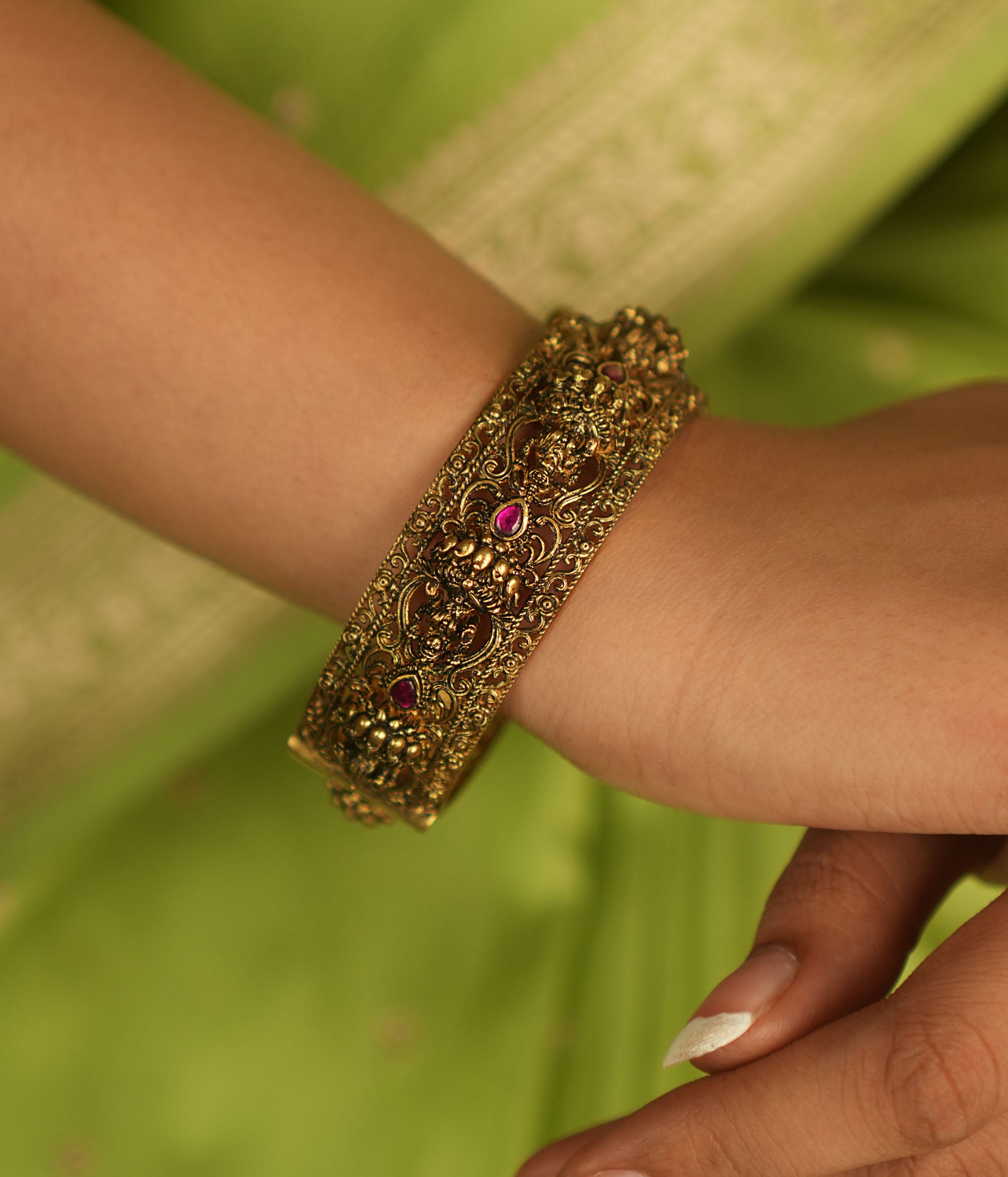 Antique gold bangle featuring Lakshmi motifs adorned with pink kundan stones, a timeless temple-inspired treasure.