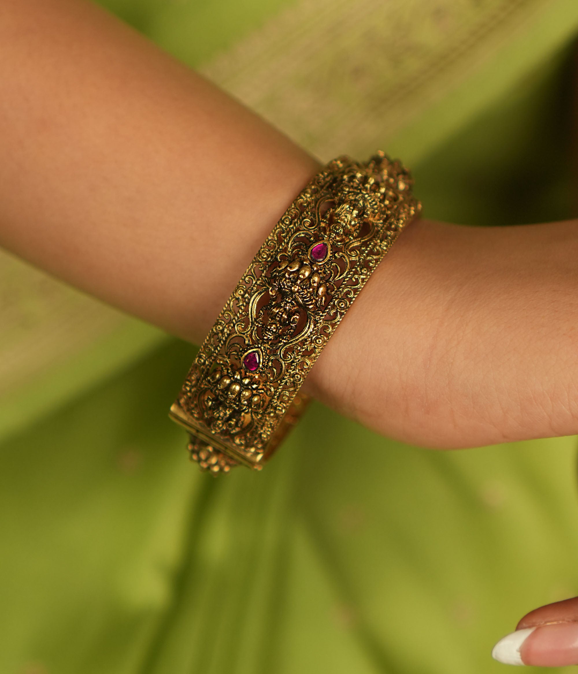 Antique gold bangle featuring Lakshmi motifs adorned with pink kundan stones, a timeless temple-inspired treasure.