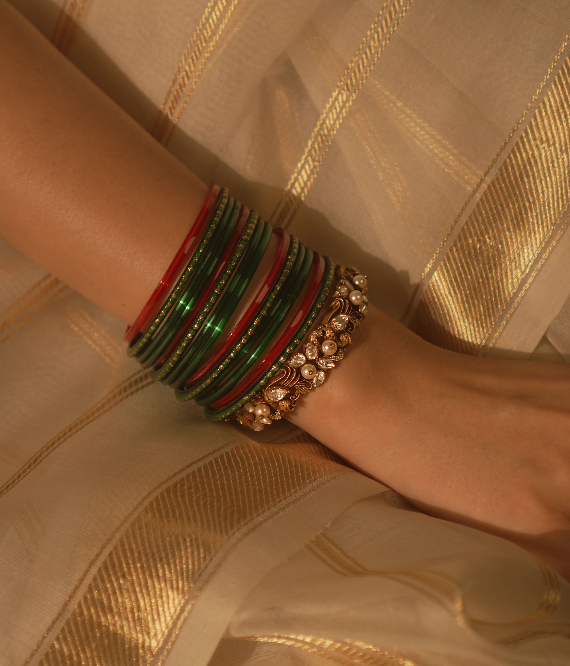 Golden temple bangle with peacock motif, Polki stones, and pearl detailing.
