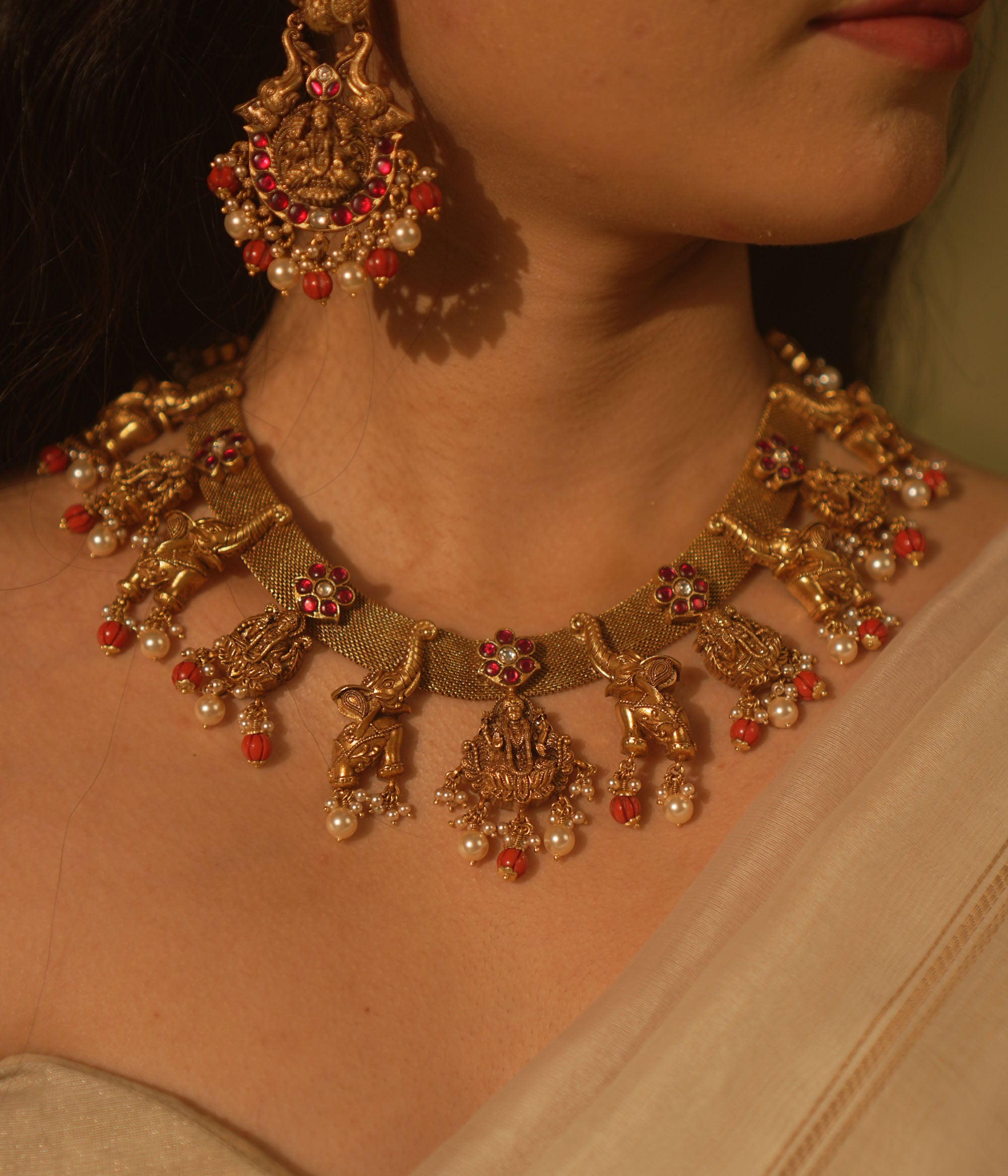 Temple collection Aamal Necklace featuring Goddess Lakshmi, elephant motifs, pink Kundan stones, pearls, and coral beads.