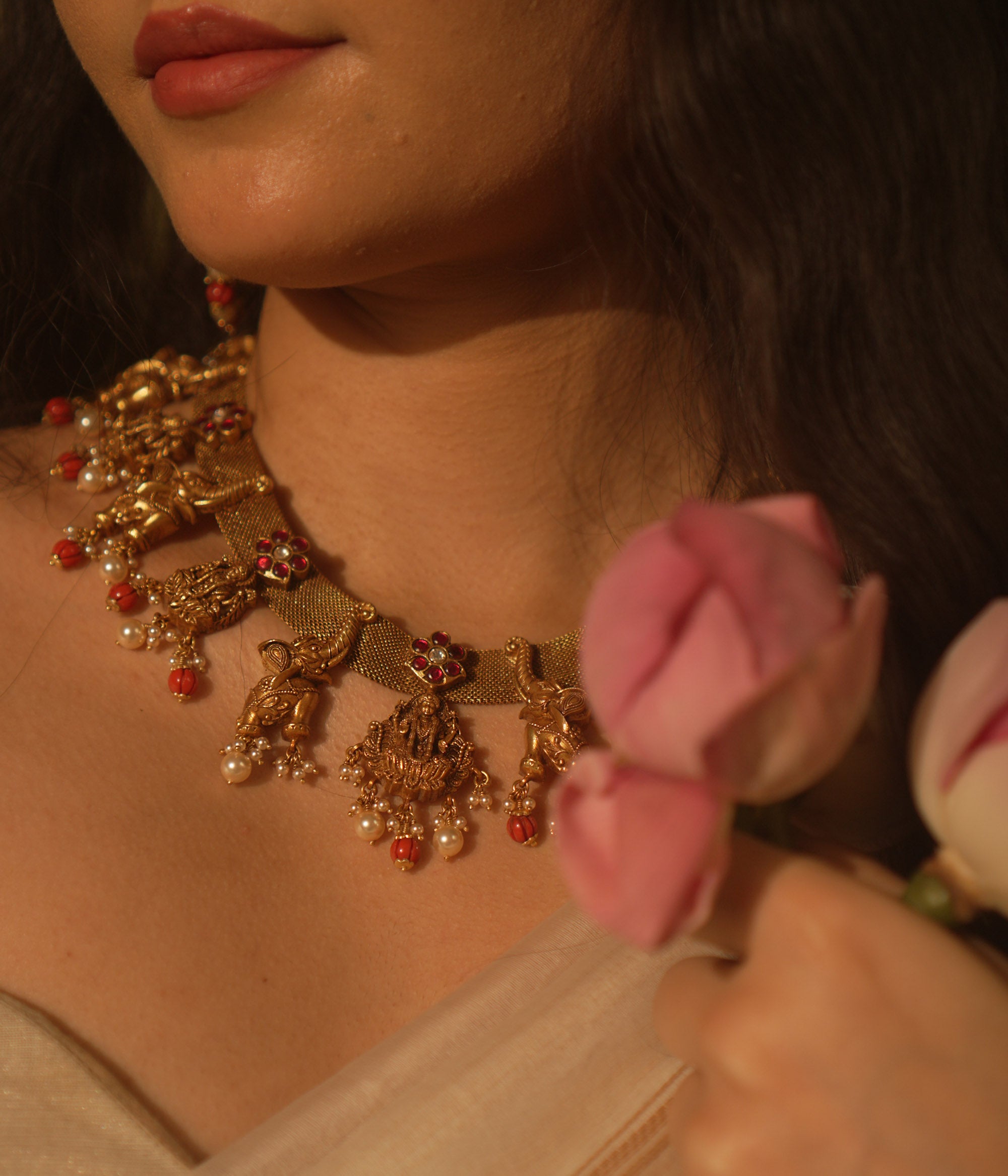 Temple collection Aamal Necklace featuring Goddess Lakshmi, elephant motifs, pink Kundan stones, pearls, and coral beads.