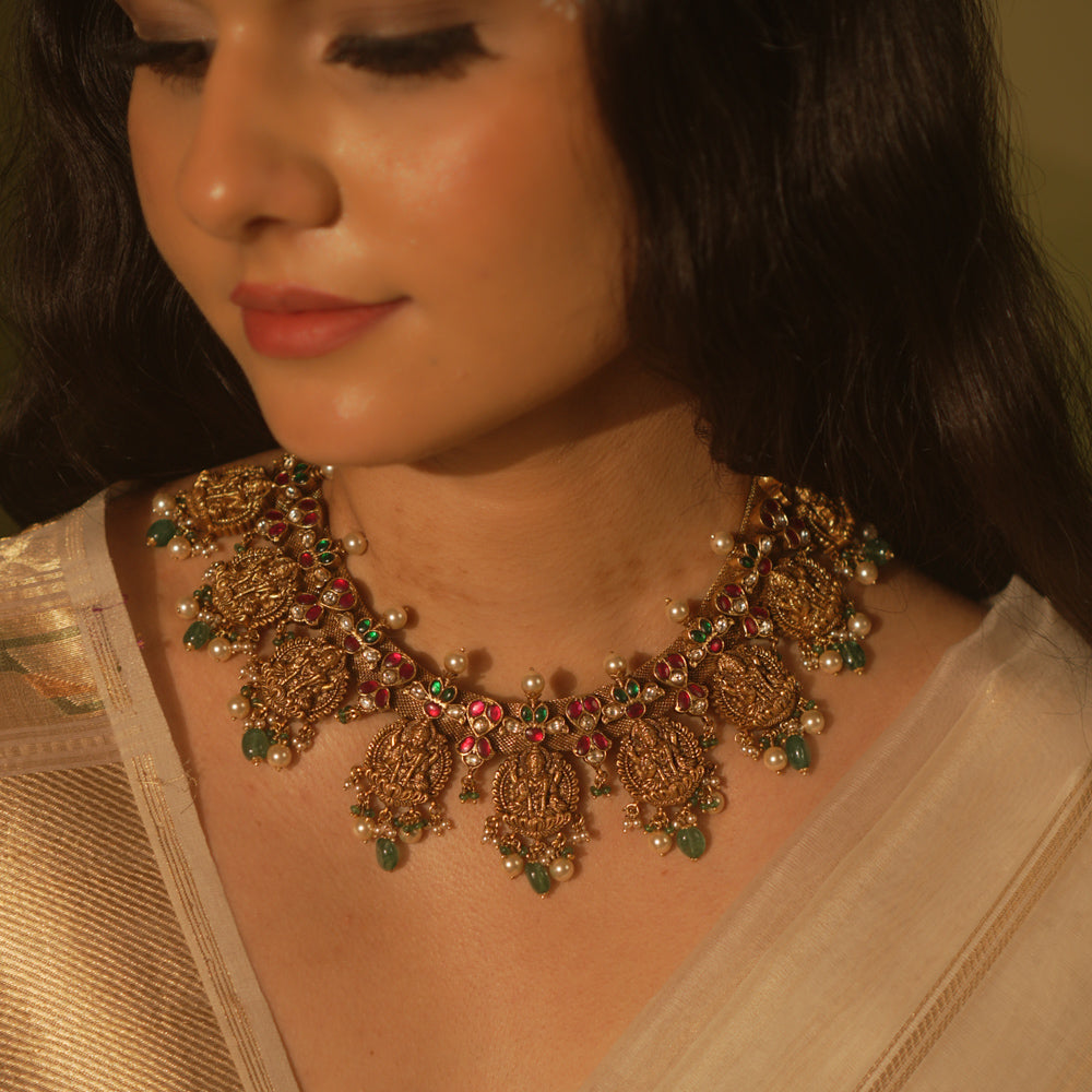 Temple collection Raahi Necklace adorned with seated Lakshmi motifs, pink and green Kundan stones, and Basra pearls.