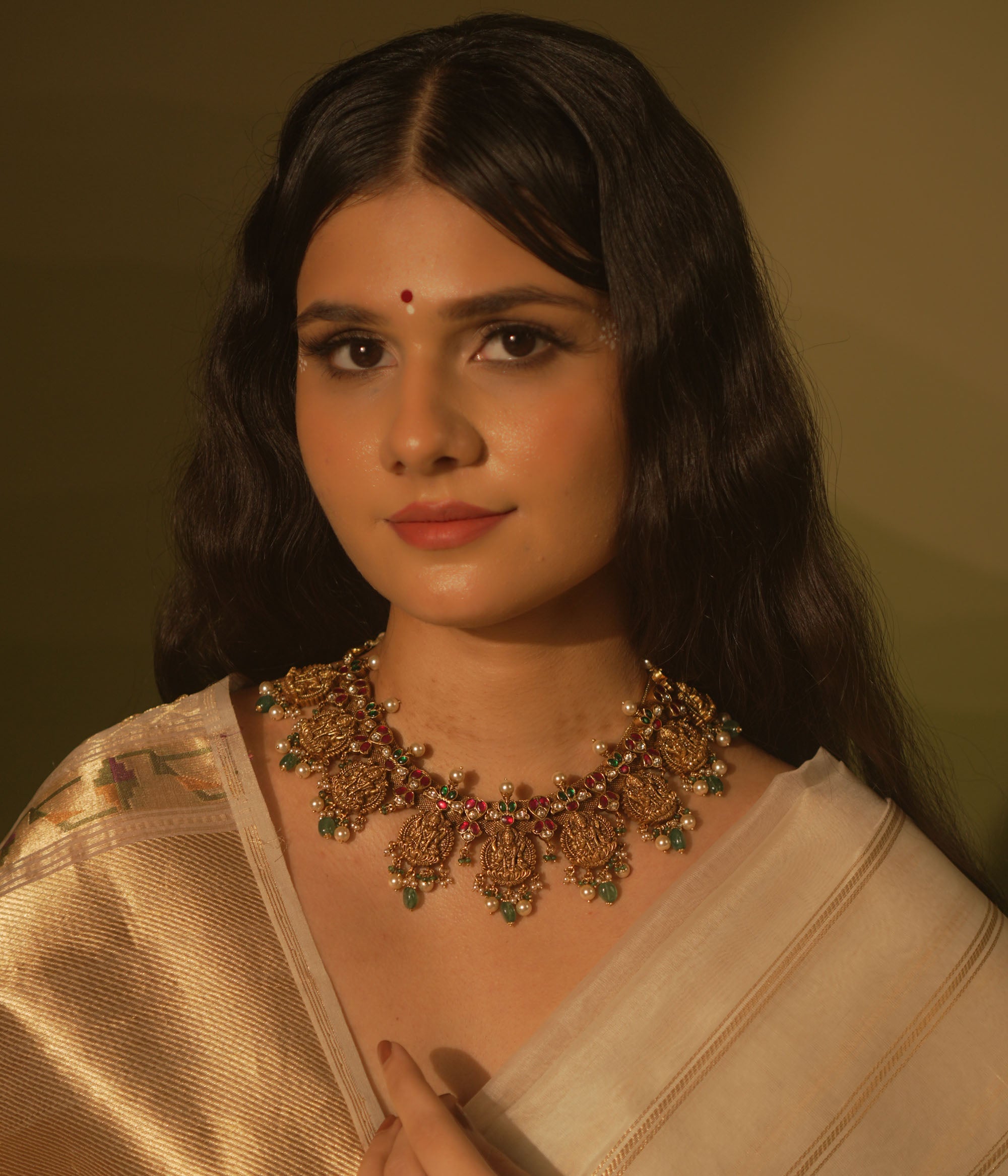 Temple collection Raahi Necklace adorned with seated Lakshmi motifs, pink and green Kundan stones, and Basra pearls.