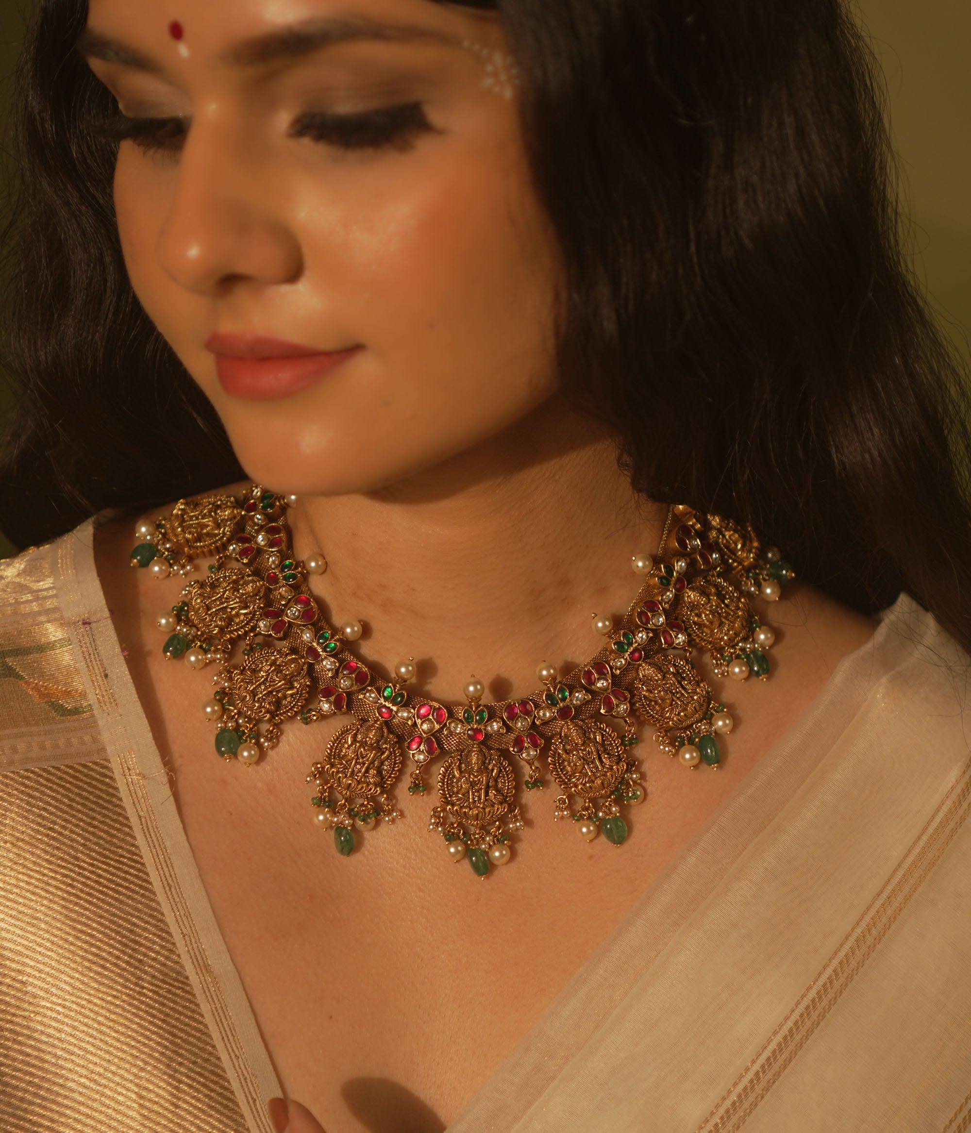 Temple collection Raahi Necklace adorned with seated Lakshmi motifs, pink and green Kundan stones, and Basra pearls.