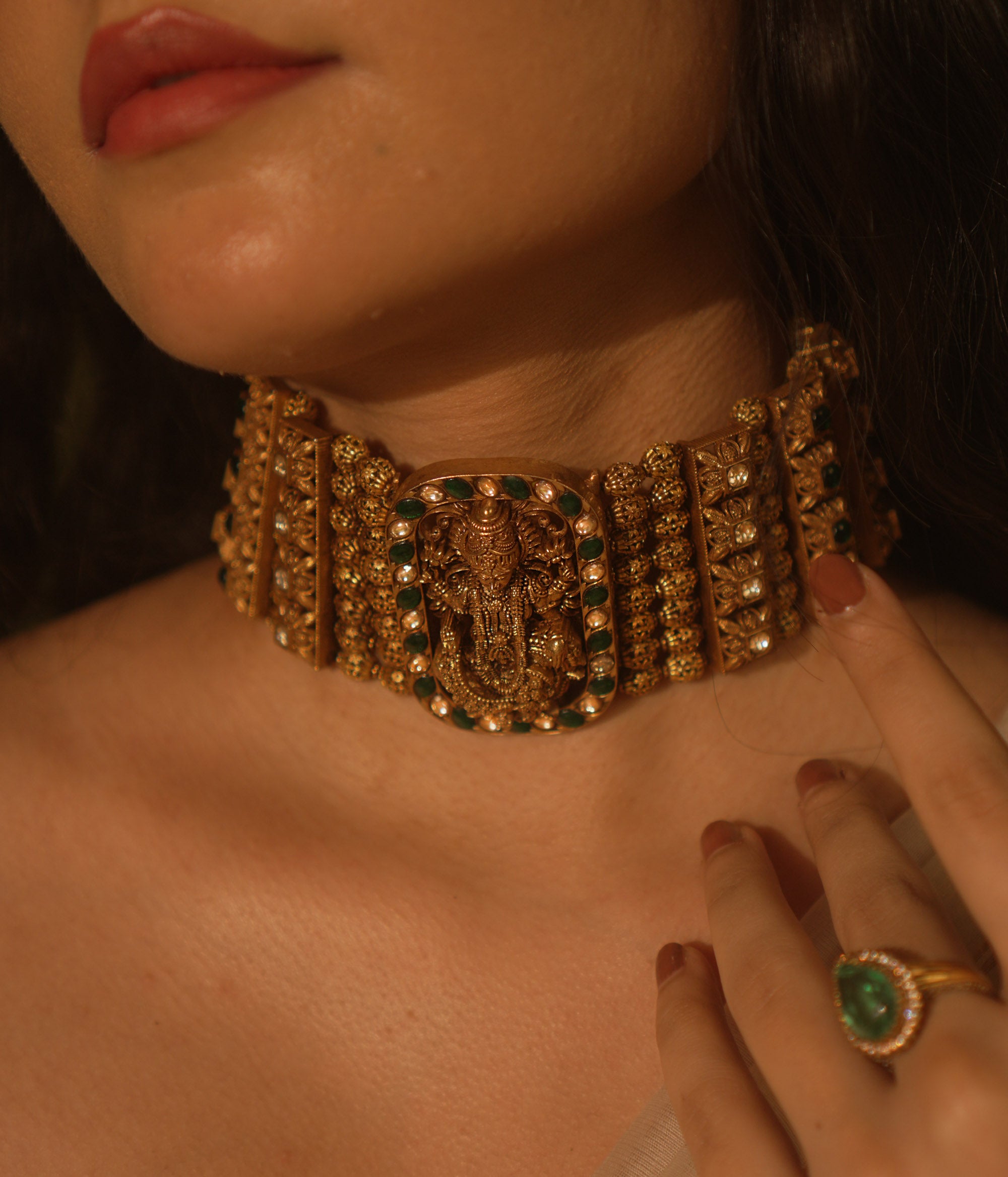Temple collection Alyaa Necklace featuring Goddess Lakshmi, floral carvings, and emerald green Kundan stones in a choker design.
