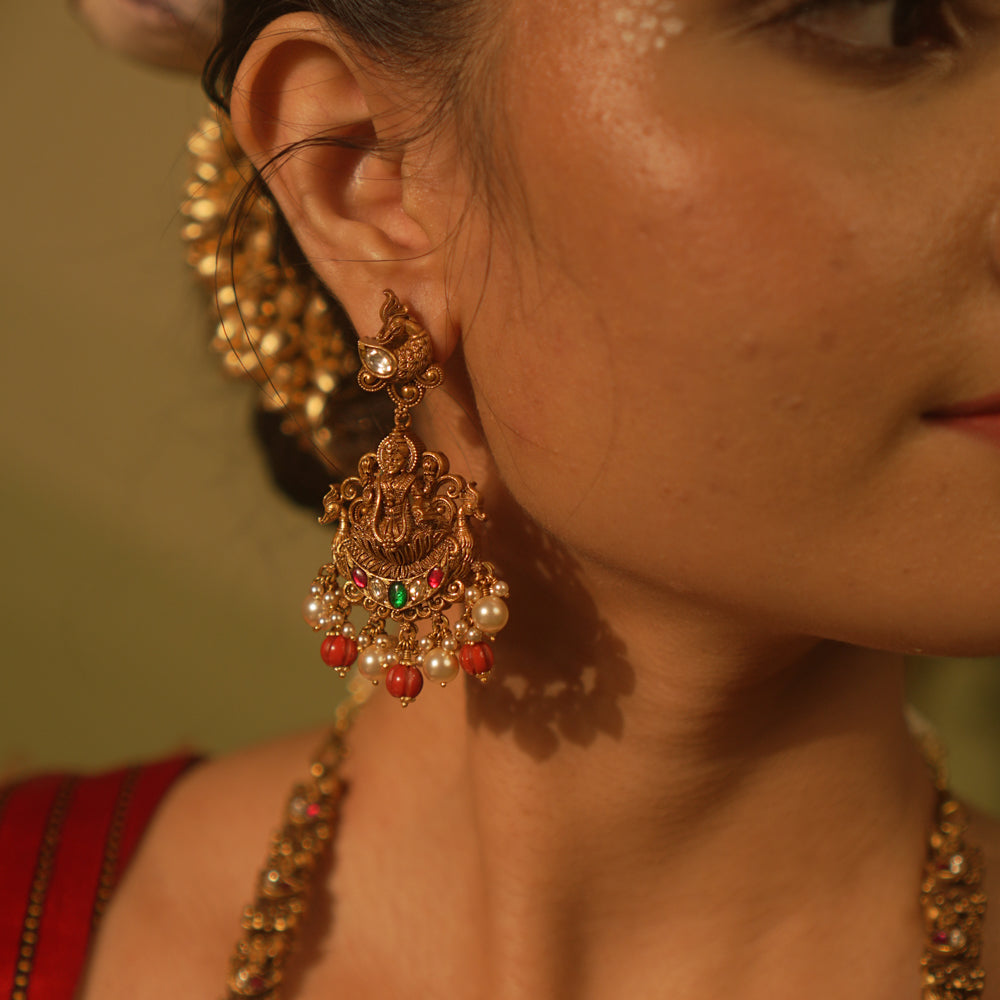 Temple-style Ganesha earrings with red and green Kundan stones, coral beads, and pearls for traditional wear.