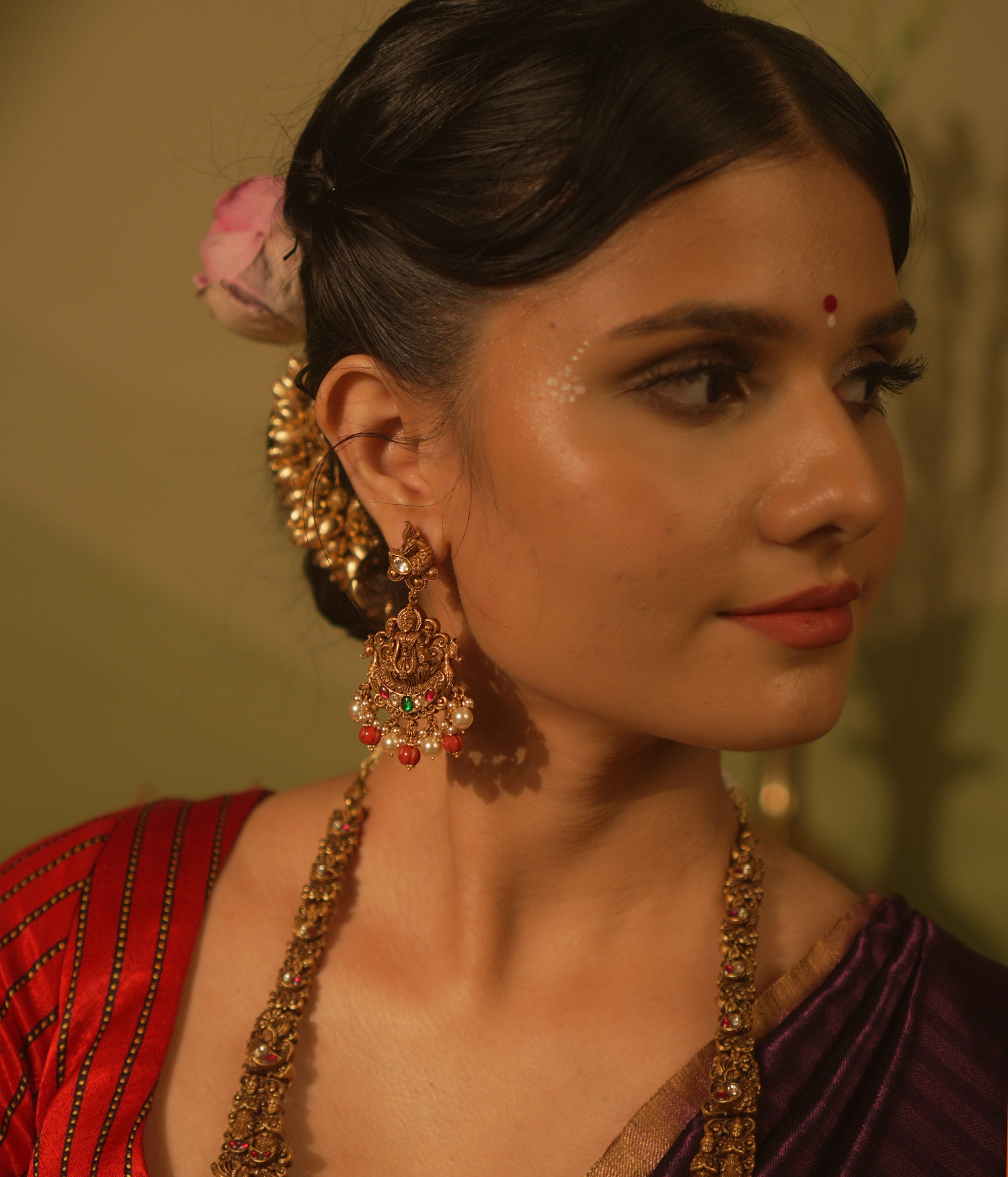 Temple-style Ganesha earrings with red and green Kundan stones, coral beads, and pearls for traditional wear.