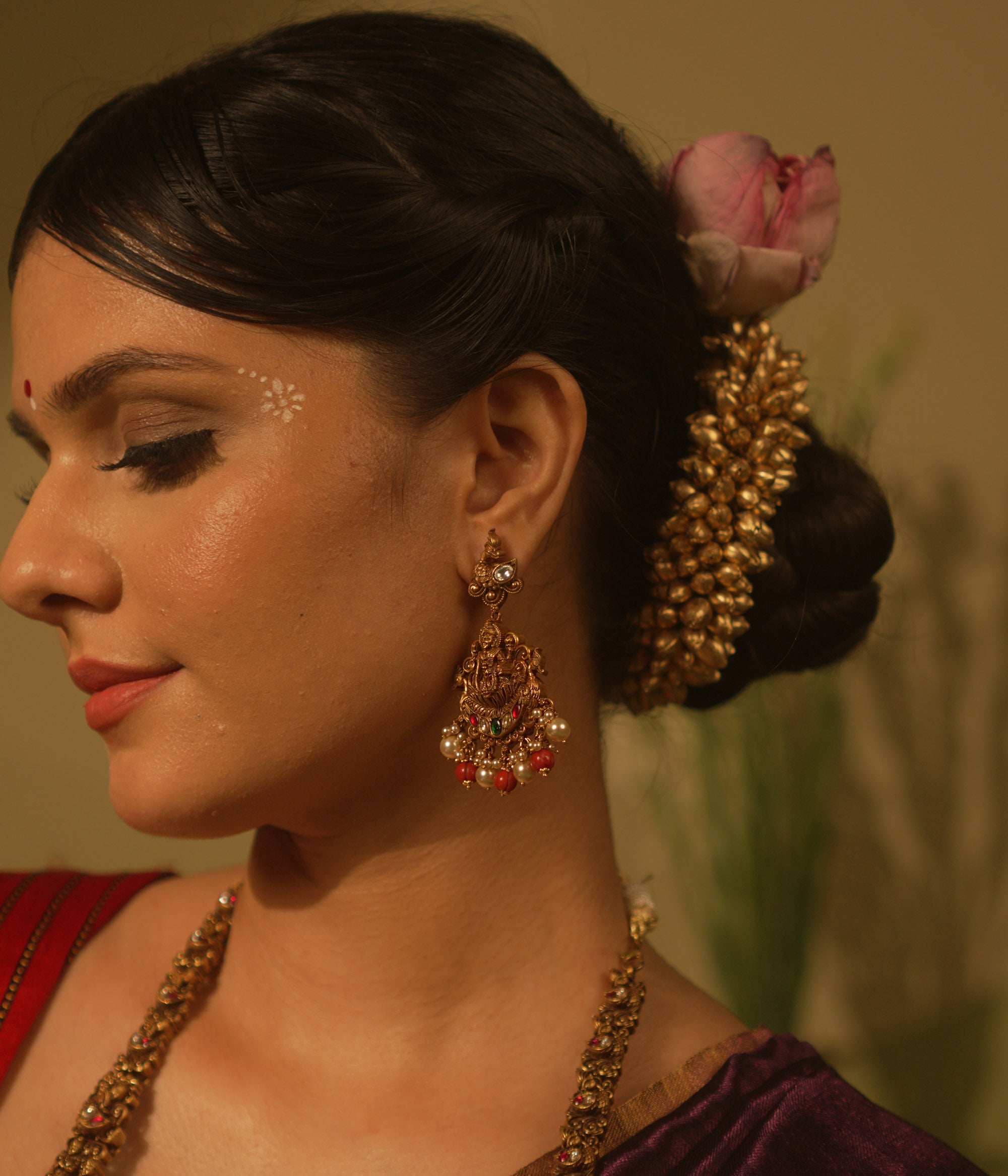 Temple-style Ganesha earrings with red and green Kundan stones, coral beads, and pearls for traditional wear.