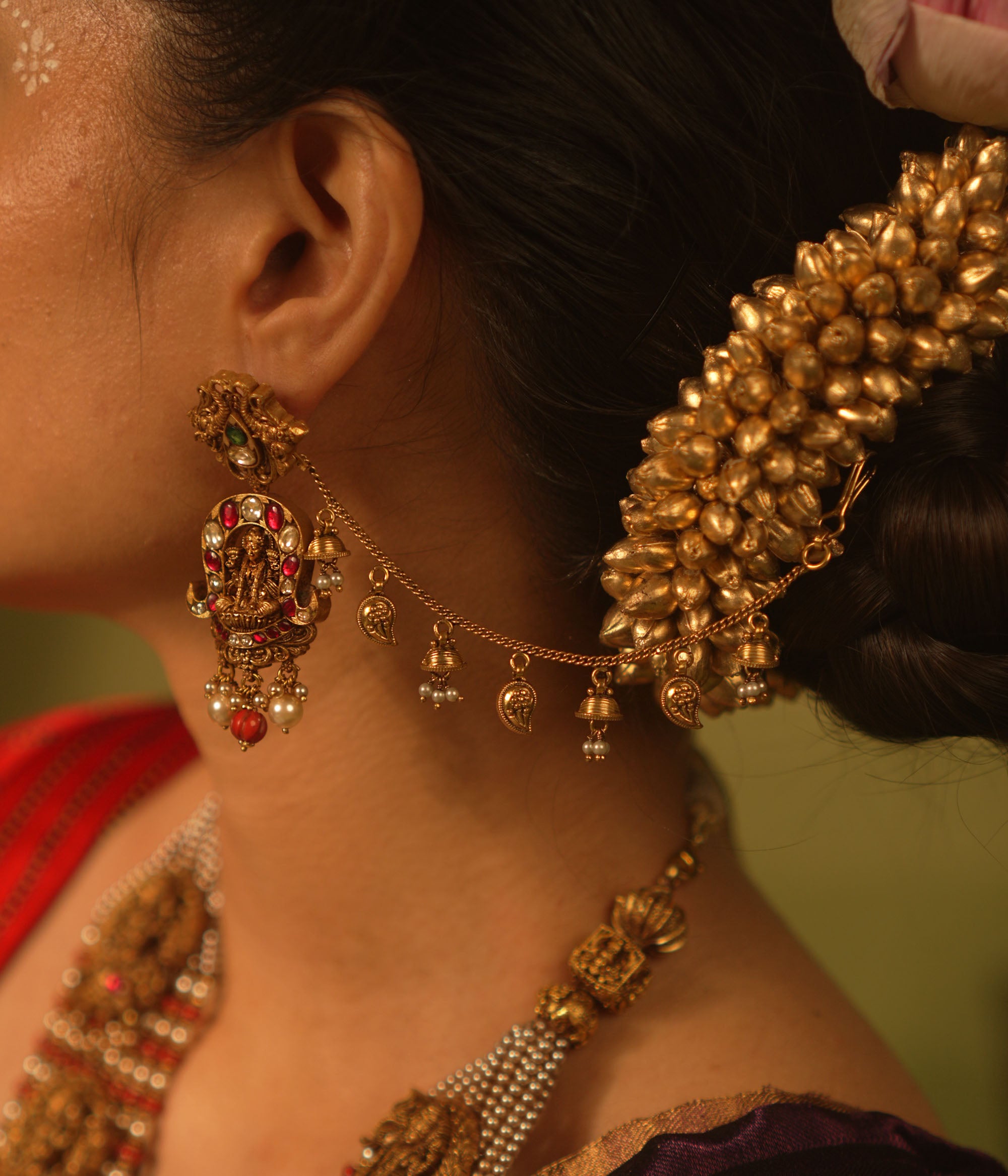 Traditional temple ear chain with Lakshmi motif, red and green Kundan stones, coral beads, and pearl danglers.