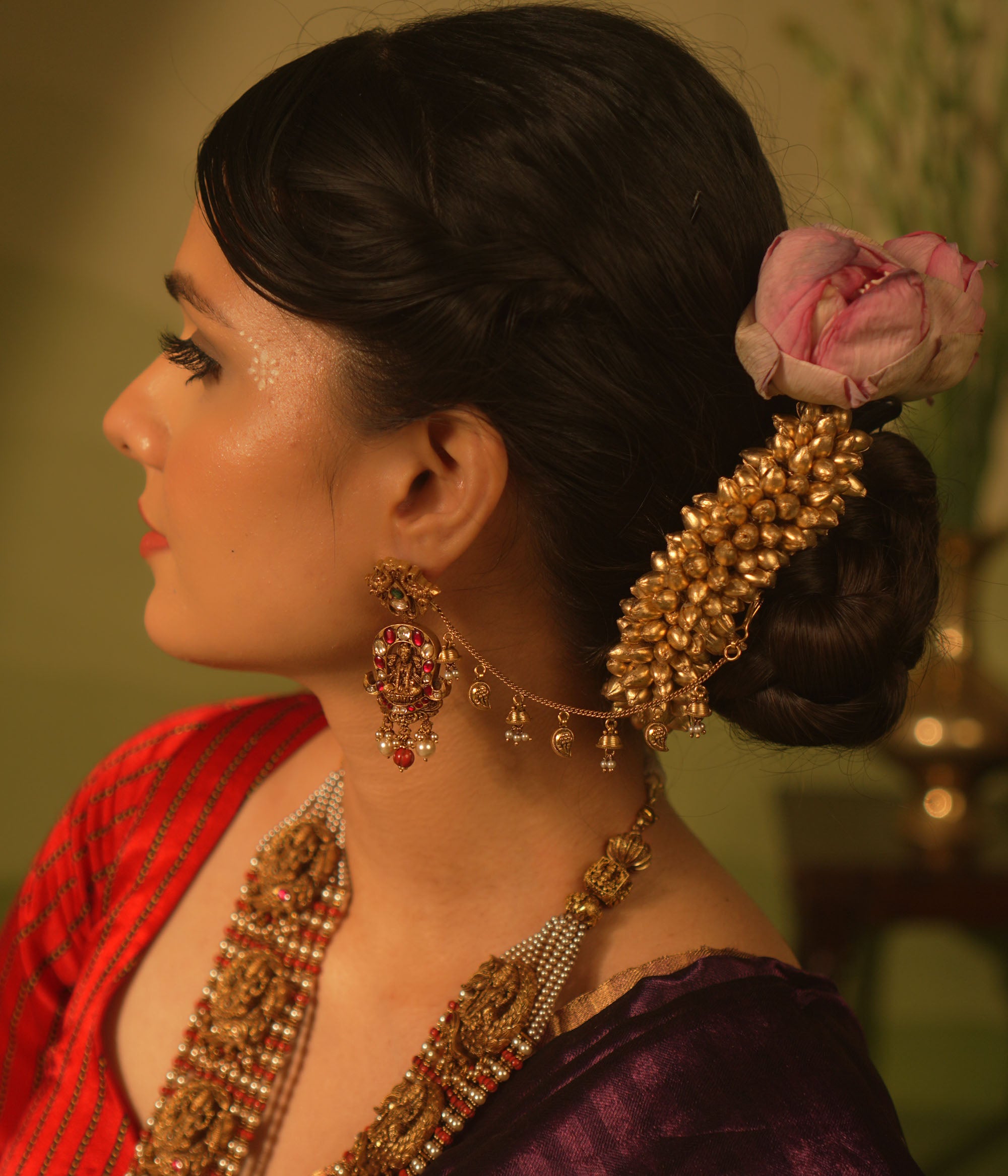 Traditional temple ear chain with Lakshmi motif, red and green Kundan stones, coral beads, and pearl danglers.