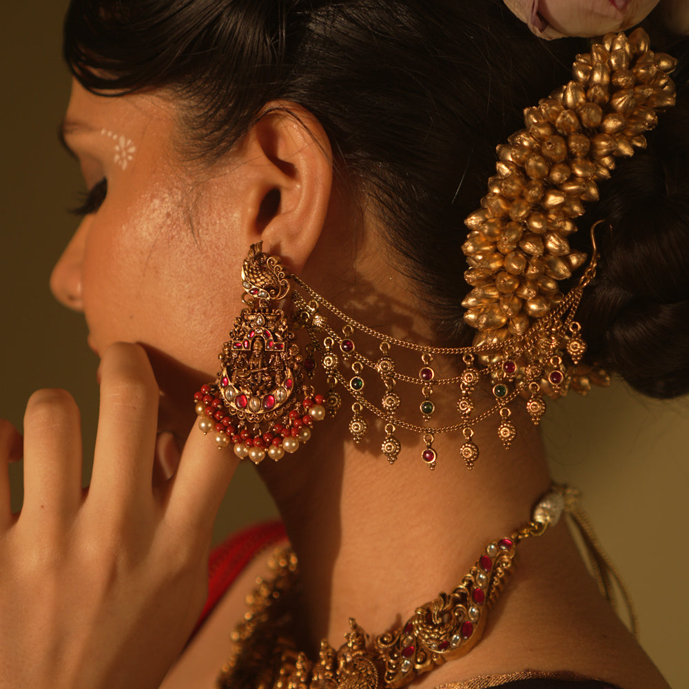 Ranjaki temple earrings with goddess motif, peacock stud, red-green Kundan, pearls, and cascading chains.