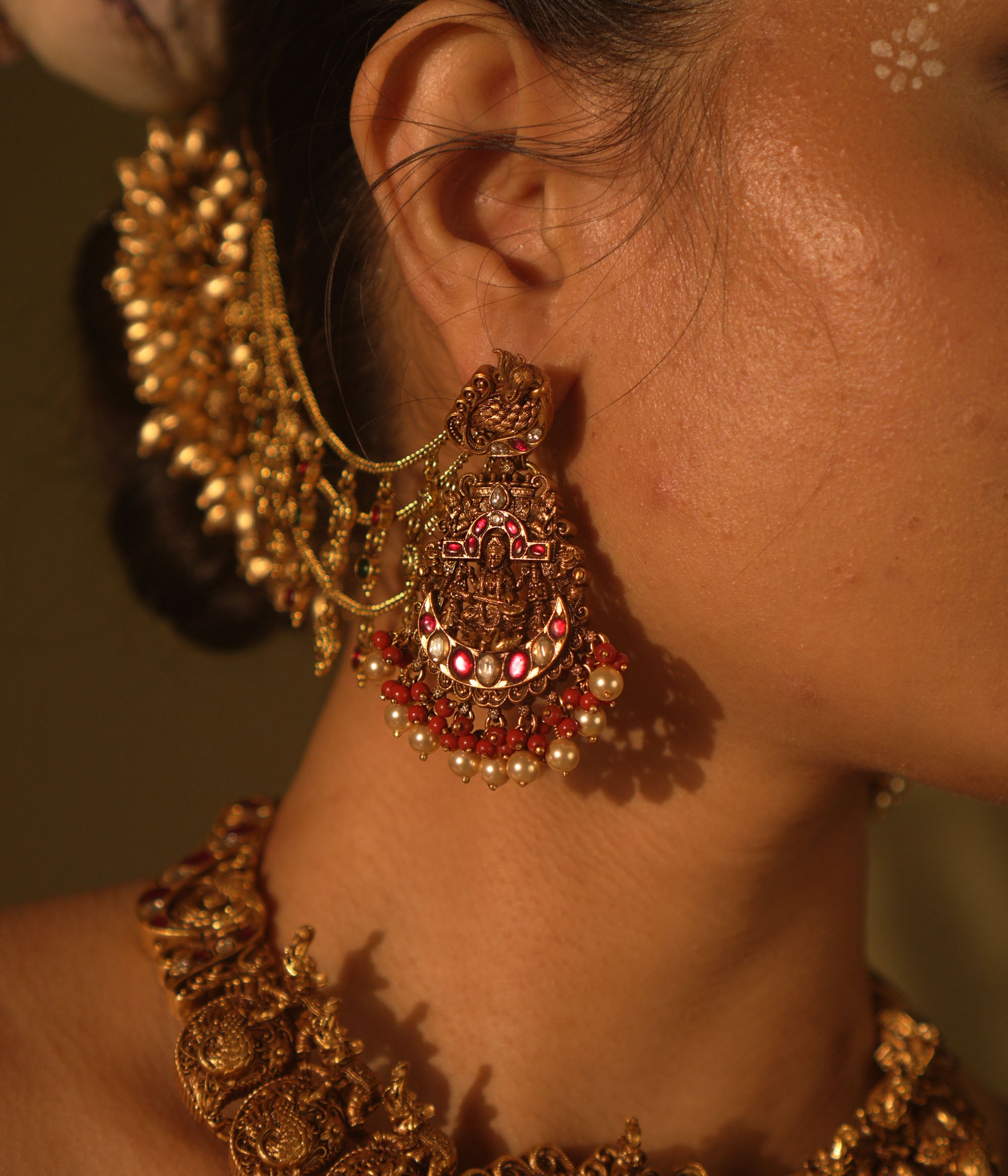 Ranjaki temple earrings with goddess motif, peacock stud, red-green Kundan, pearls, and cascading chains.