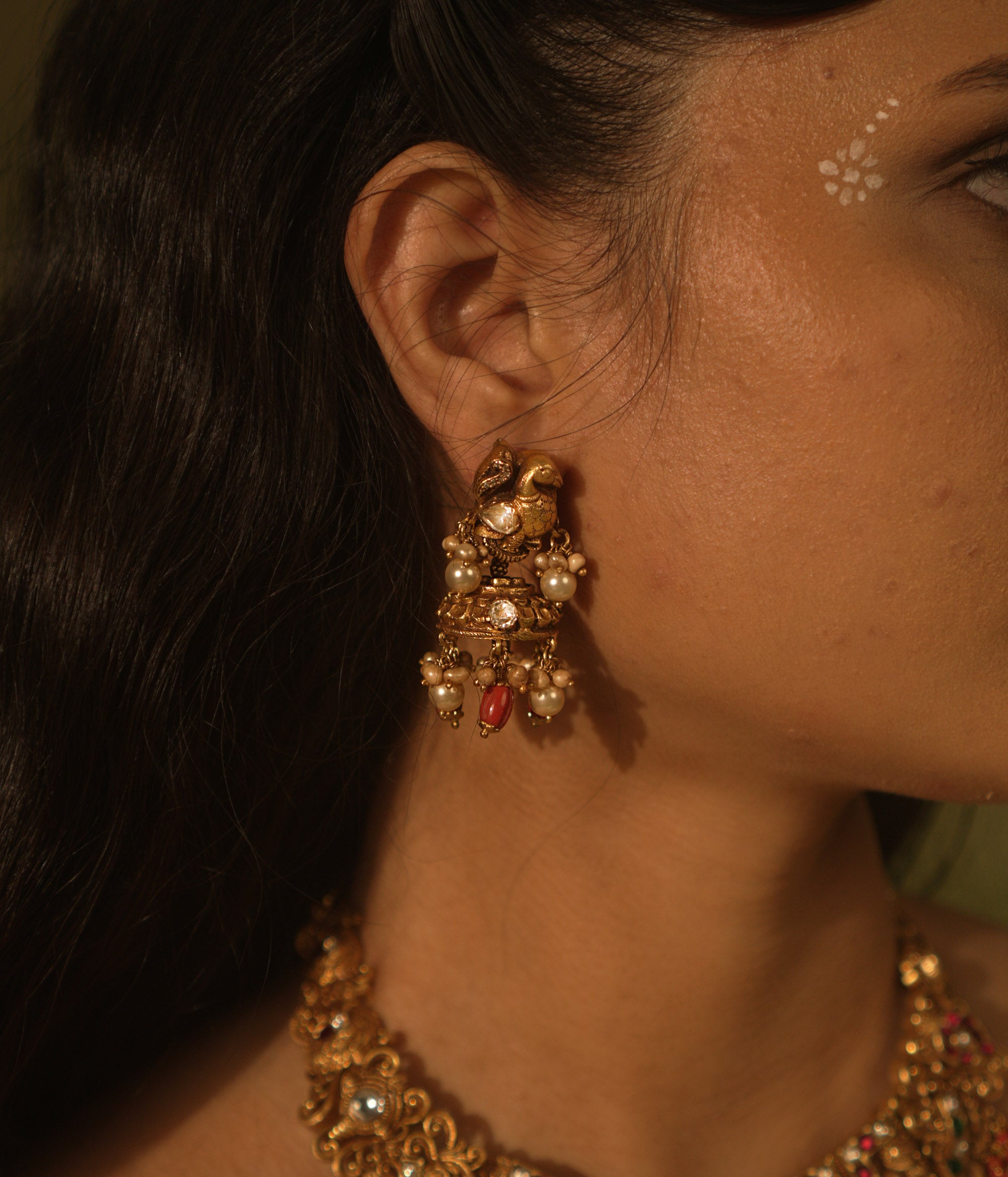 Temple jhumkas with peacock motifs, coral details, and Basra pearls—blending tradition with vibrant beauty.