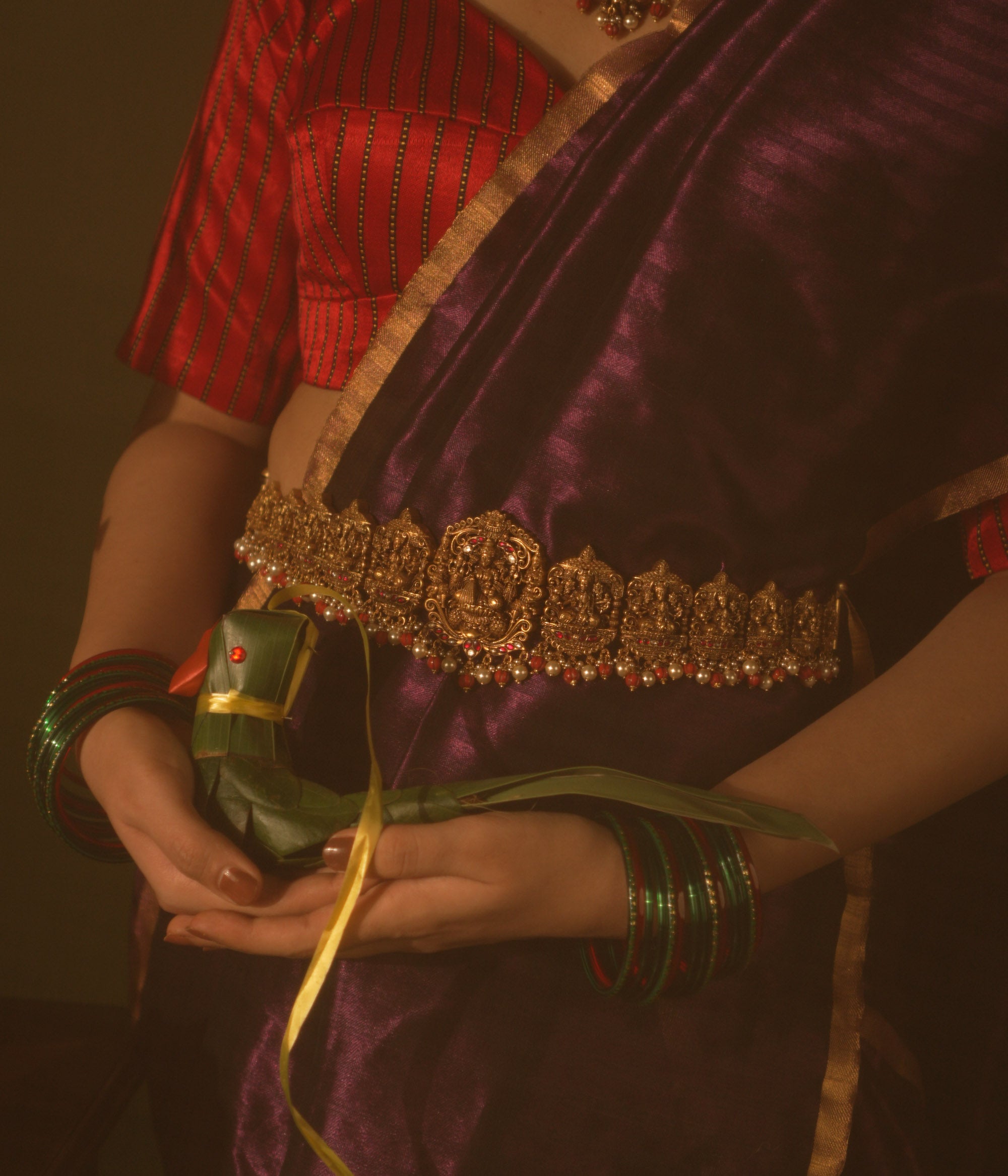 Temple vaddanam with Lakshmi motif, red-white Kundan stones and pearls worn over silk saree.