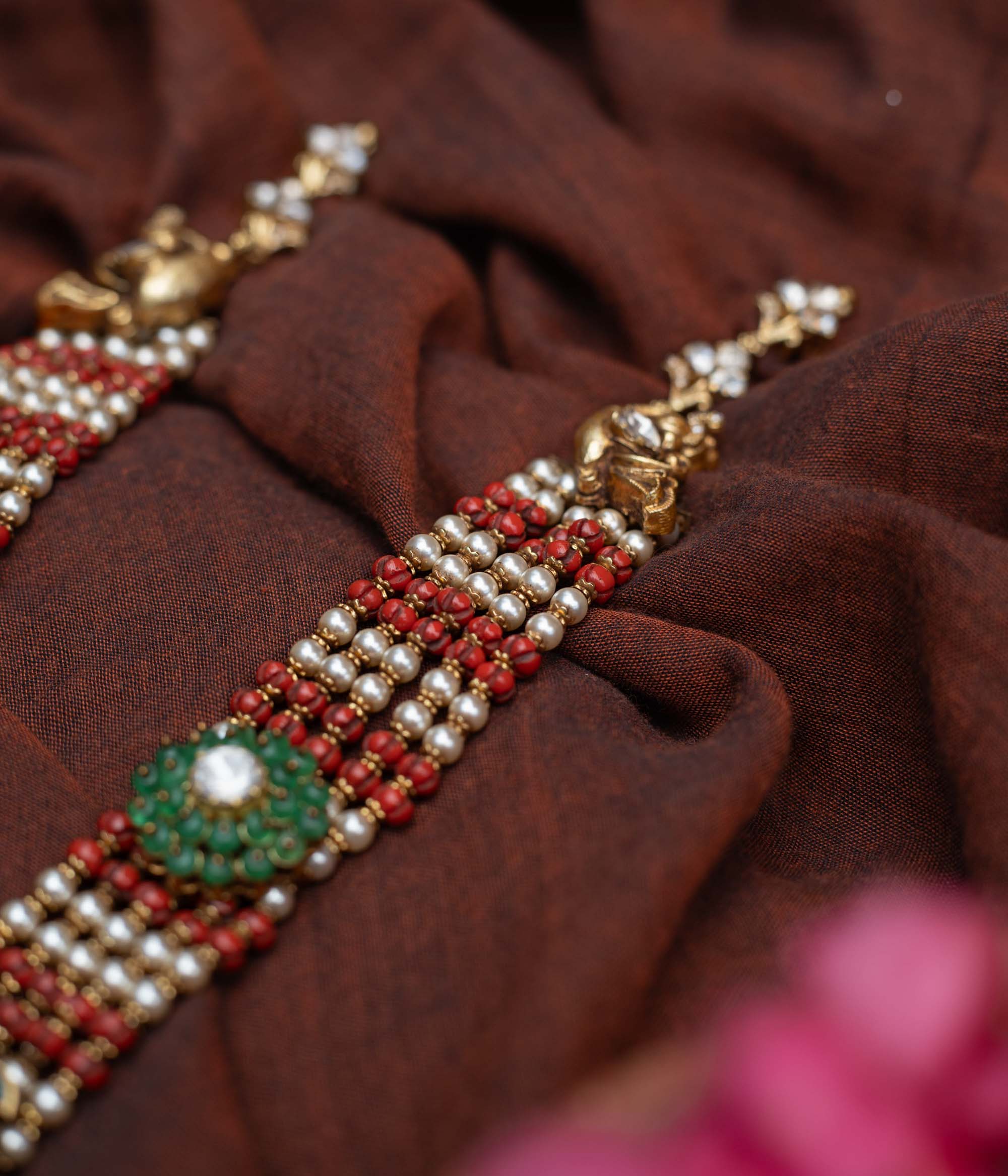 Antique gold-embossed 92.5 sterling silver Devi Lakshmi Necklace inspired by temple art, featuring vibrant green and white stones and cascading pearls from the divine central motif, embodying traditional elegance and spiritual grace.