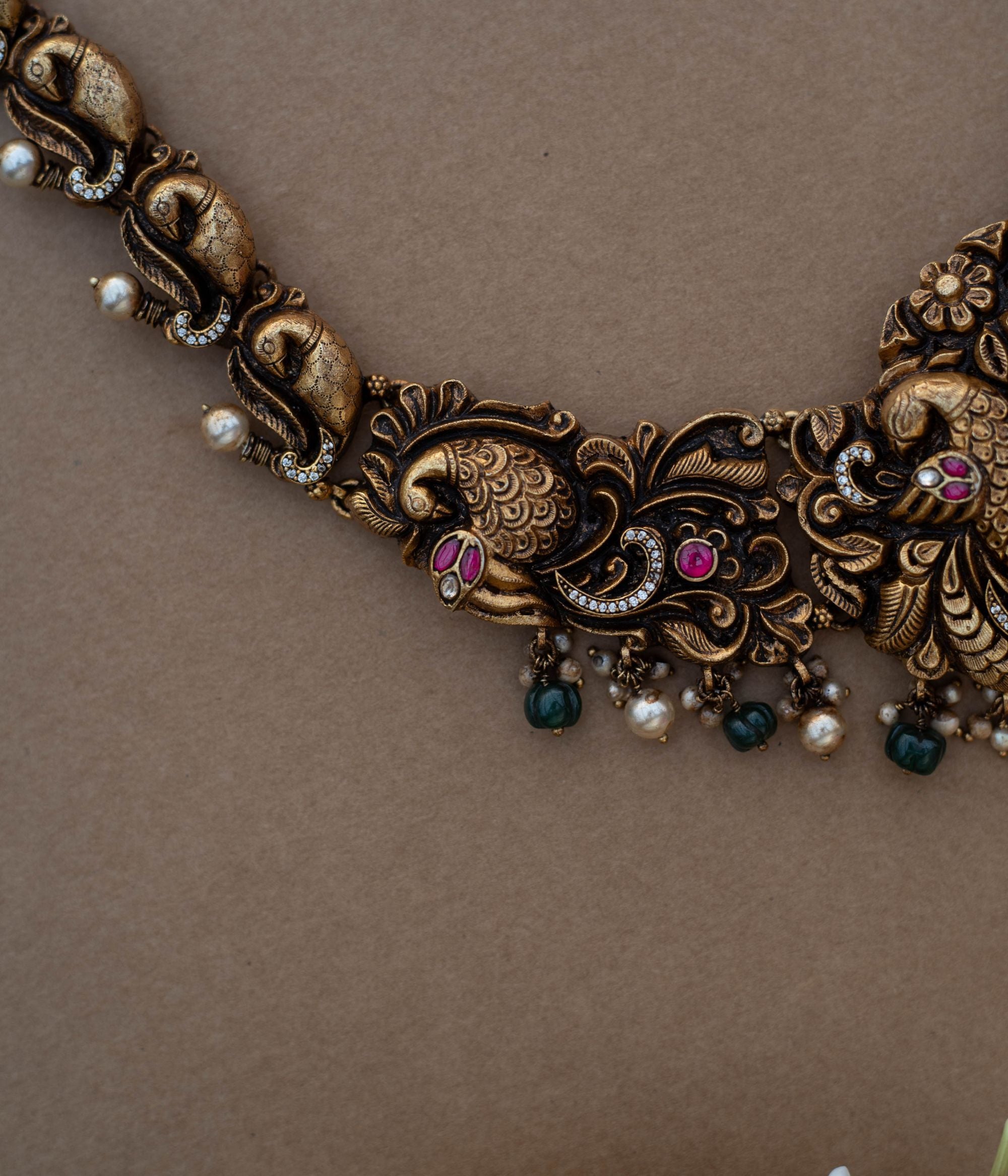 Traditional Rakni Necklace in 92.5 Sterling Silver and 22ct Gold Plated, featuring Kundan stones, green beads, and white pearls, with intricate peacock design and antique gold finish.