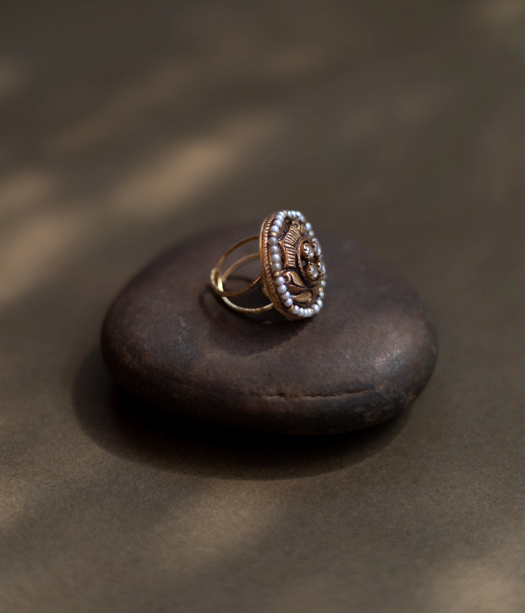 Heritage Glow Antique Ring: a mirror to ancient souls, encircled by golden carvings and a pearl halo. A tiny bird whispers tales of heritage on your finger.