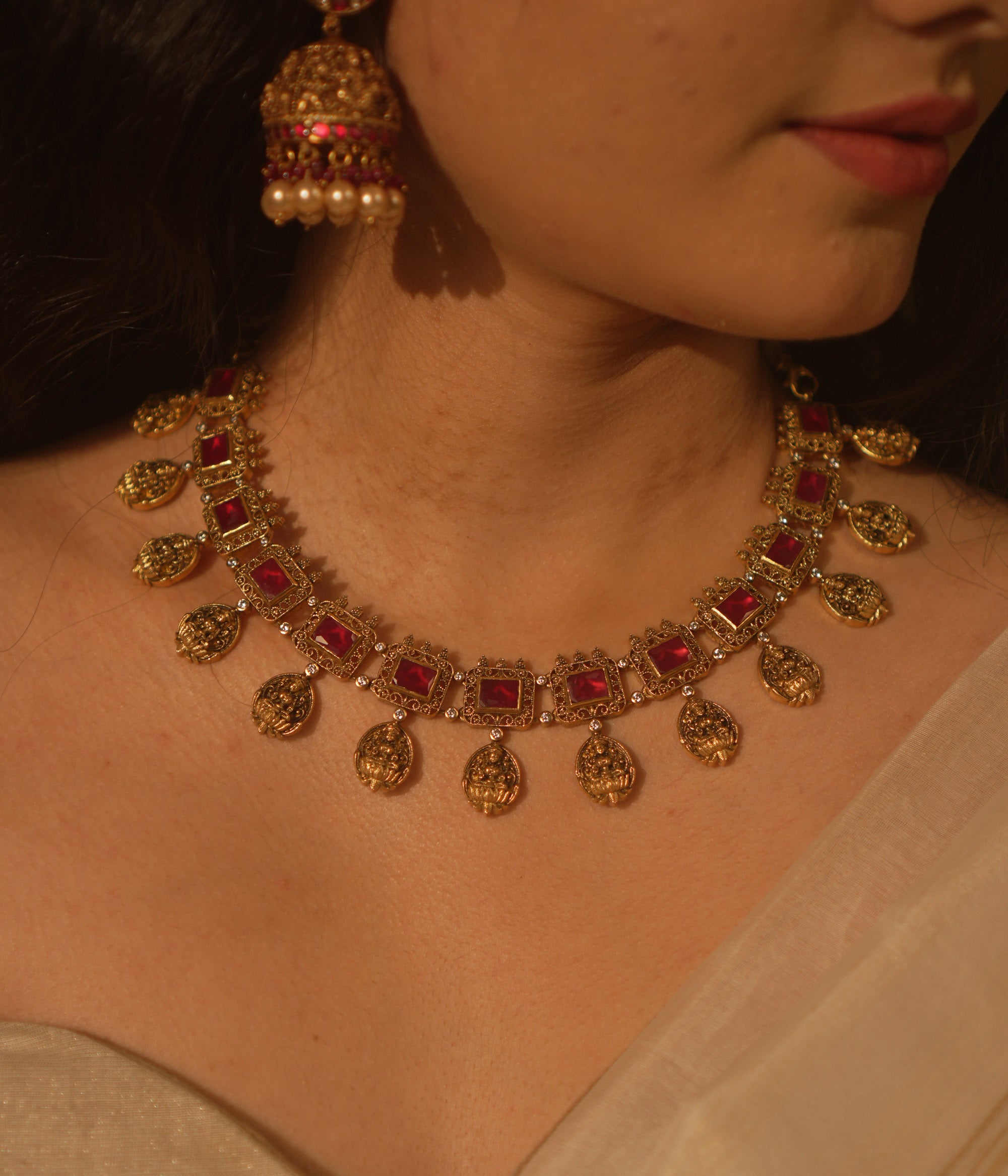 Temple-inspired necklace with red gemstones and Lakshmi motifs, blending divine elegance and traditional craftsmanship.