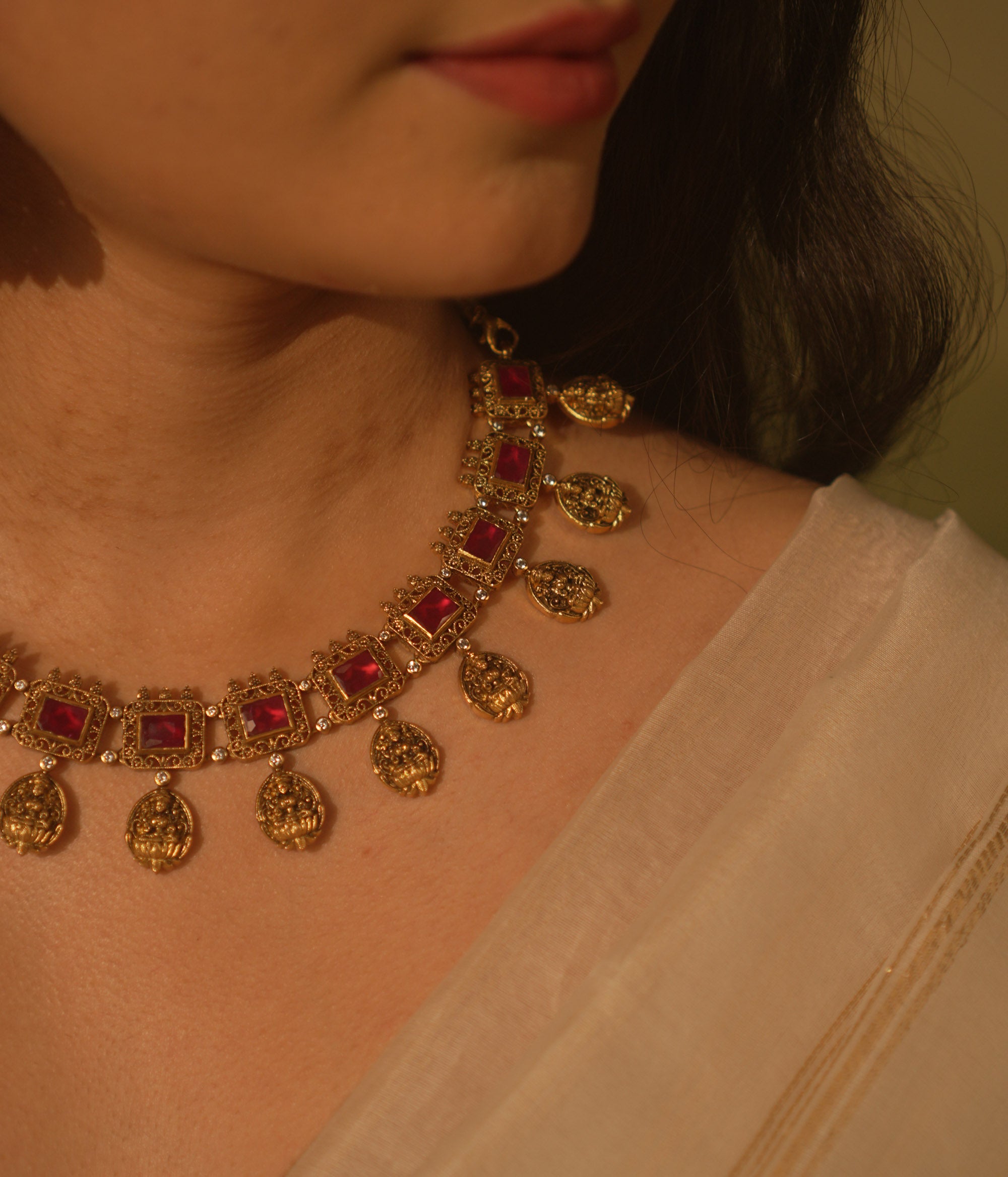 Temple-inspired necklace with red gemstones and Lakshmi motifs, blending divine elegance and traditional craftsmanship.