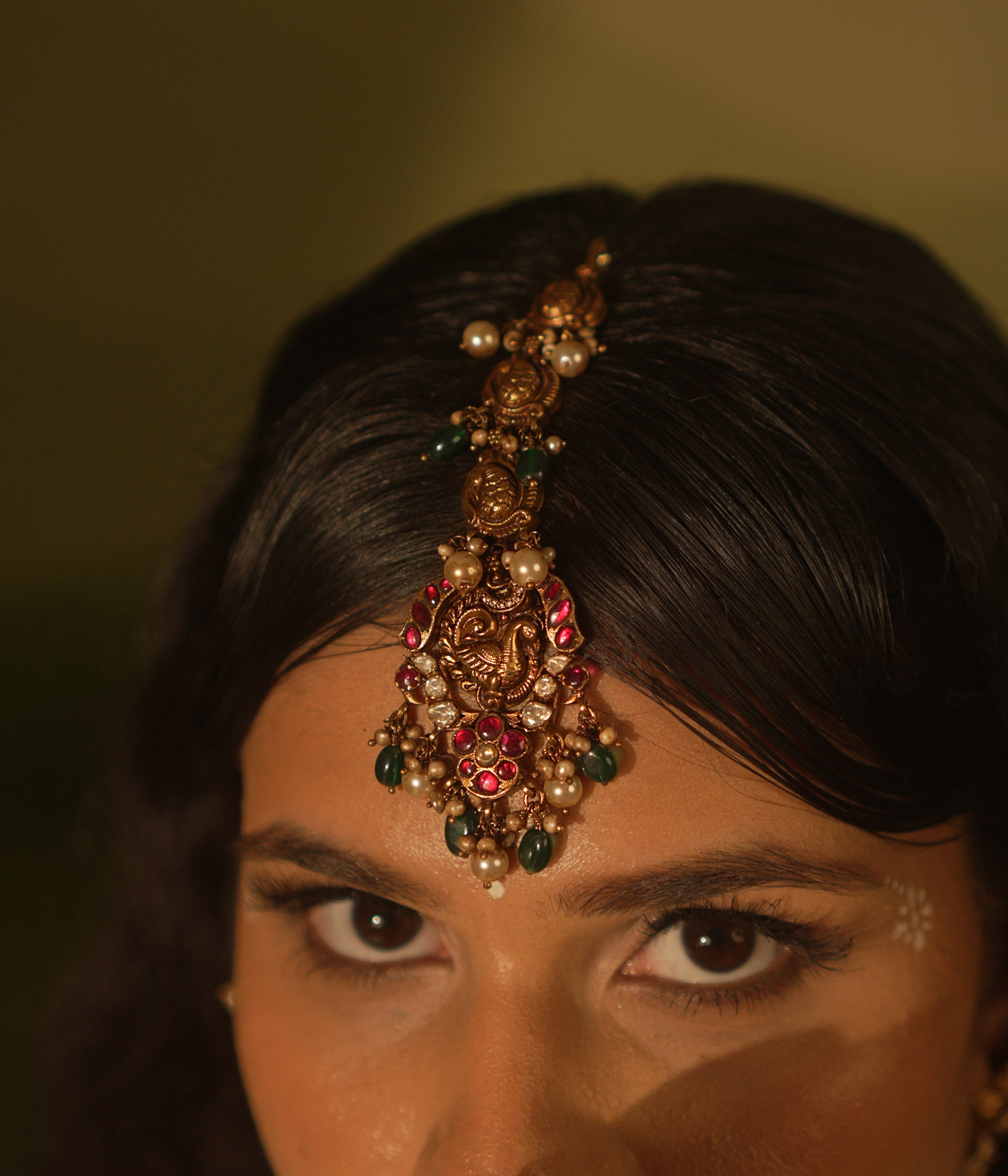 Temple collection maangtika featuring peacock and floral designs with Kundan stones, pearls, and emerald beads for traditional elegance.