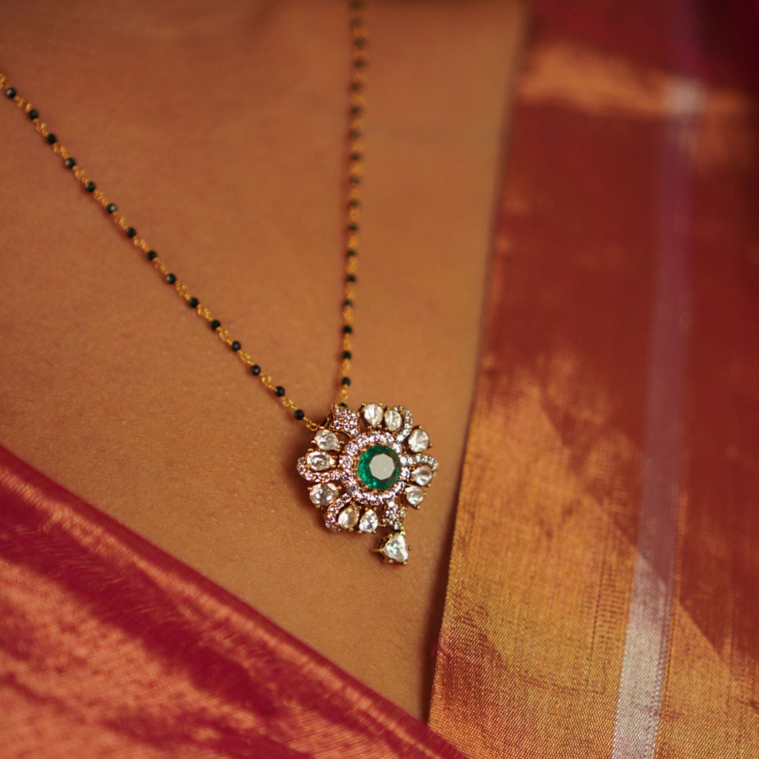 This pendant showcases a radiant floral design with shimmering polki stones, accented by a vibrant green gemstone for a touch of elegance.