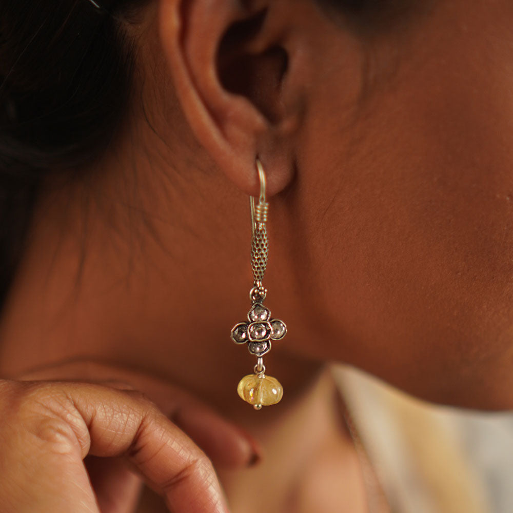 The Gatha earrings, crafted in oxidized silver, showcase delicate white kundan stones and vibrant yellow beads. With their elegant drop design, they exude a timeless allure, embracing the charm of artisanal craftsmanship and the beauty of handcrafted uniqueness.