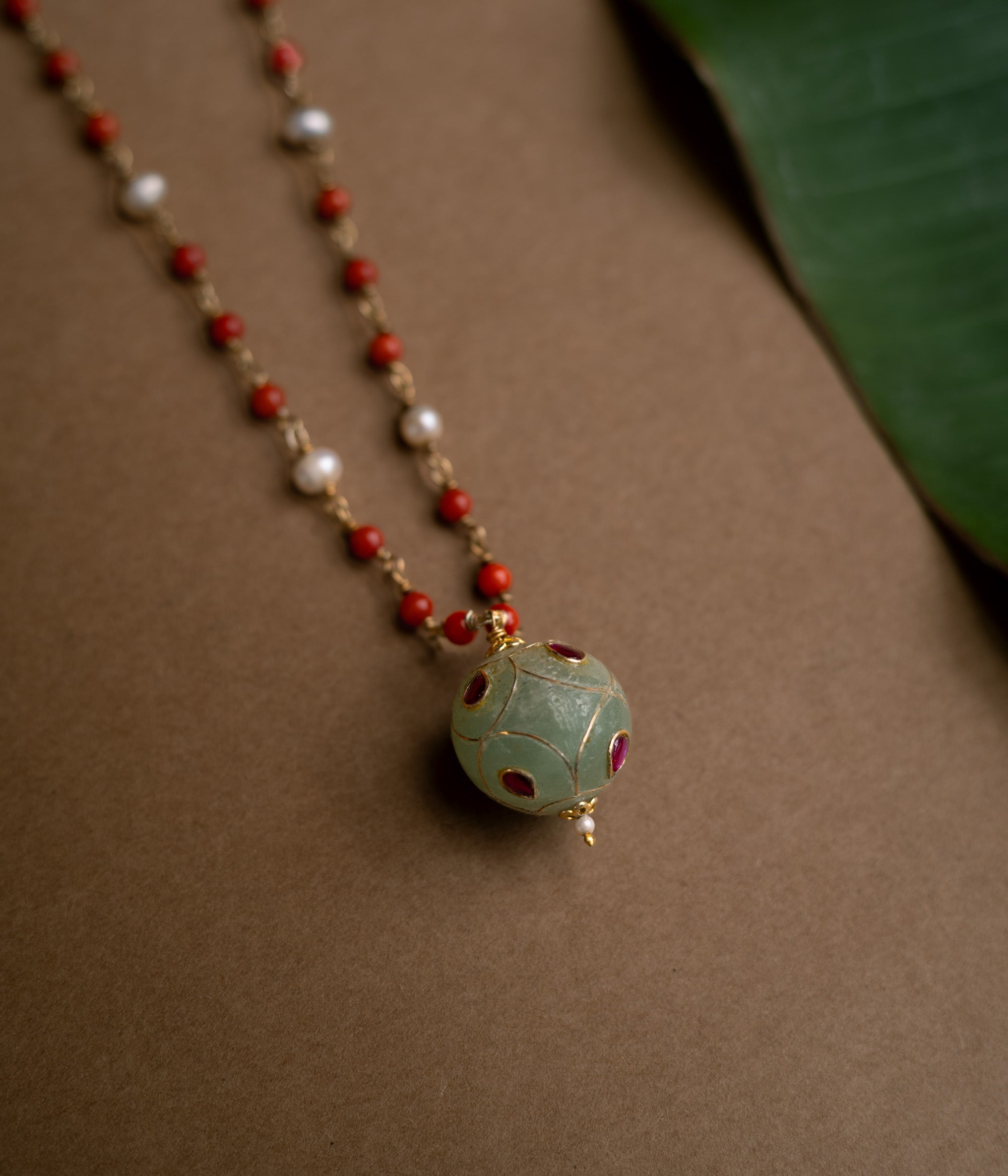 Hue collection chain with coral beads, pearls, and green stone sphere with red floral motifs.