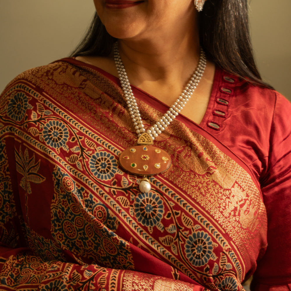 Woman wearing a terracotta pendant necklace with pearl strings from the Hue Collection.