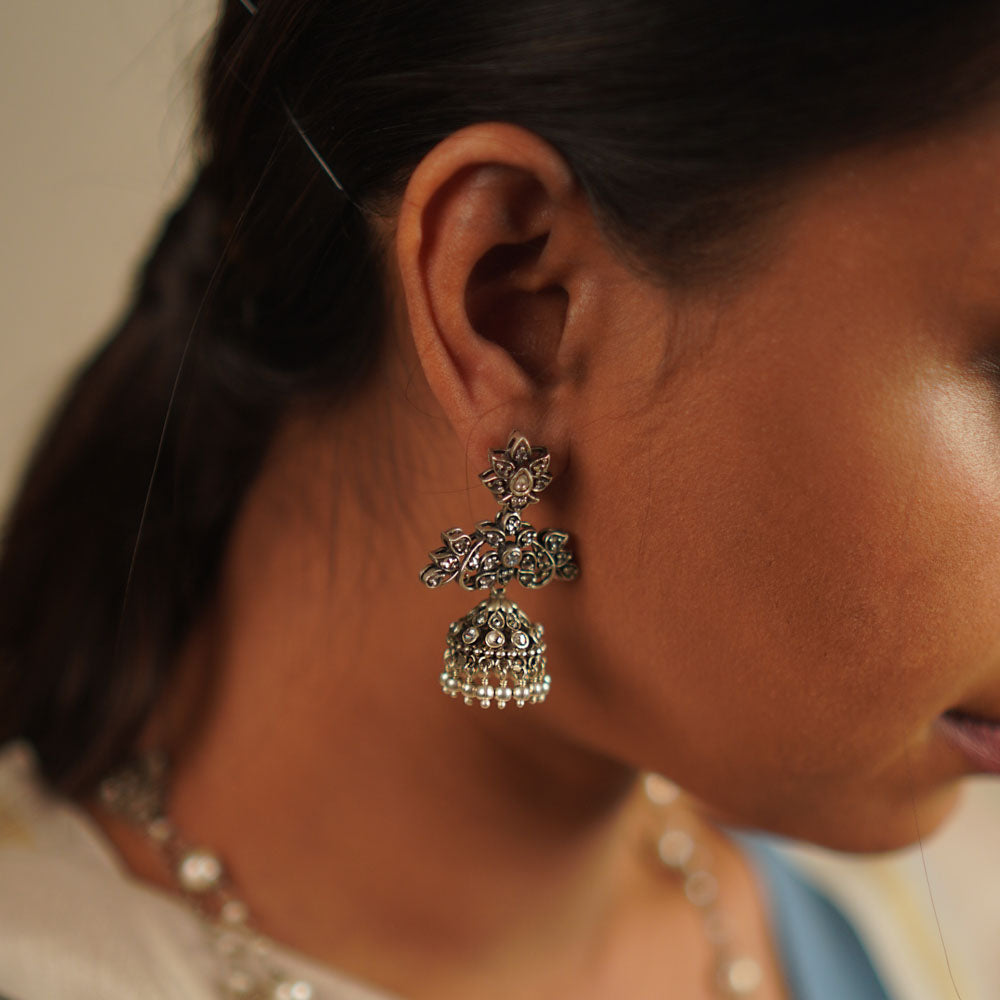 The Heti earrings, meticulously handcrafted in oxidized silver, showcase intricate detailing that reflects the essence of Indian heritage. Embellished with radiant white kundan stones, these jhumkas seamlessly blend tradition with contemporary elegance.