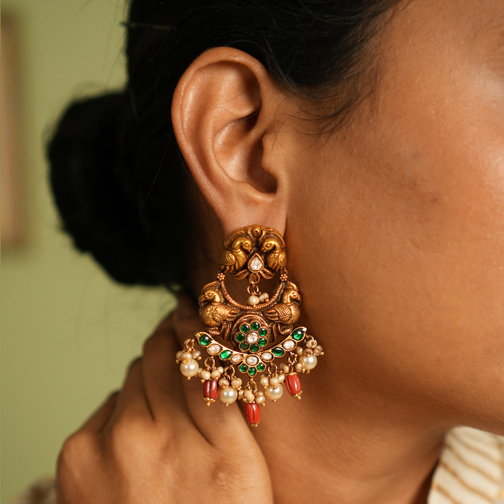 Exquisite gold-plated silver Chandbali earrings featuring a graceful peacock design, adorned with vibrant green Kundan stones, shimmering white Kundan stones, delicate pearls, and striking red beads, blending traditional elegance with timeless craftsmanship