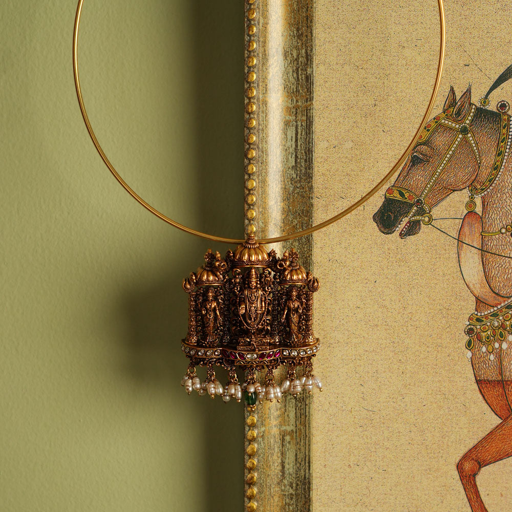 Magnificent gold-plated silver temple jewelry pendant featuring Lord Perumal in an intricate design. Adorned with radiant white and red Kundan stones, elegant green beads, and delicate white pearls, this pendant offers both single and double hooks for versatile styling, making it a perfect blend of devotion and timeless craftsmanship.