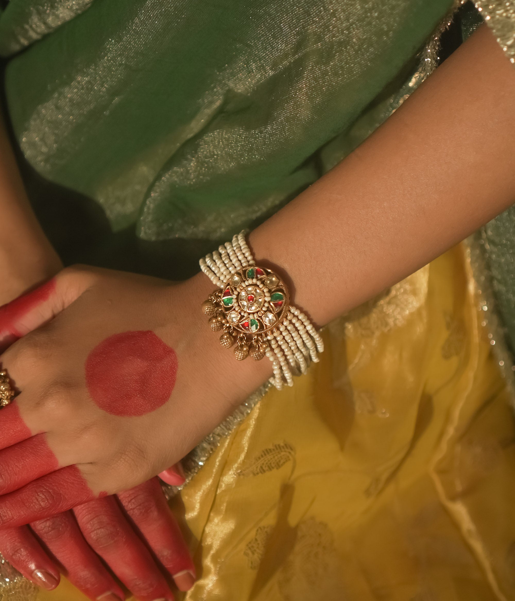 Bracelet with beaded pearls and a gold centerpiece studded with red and green Kundan.