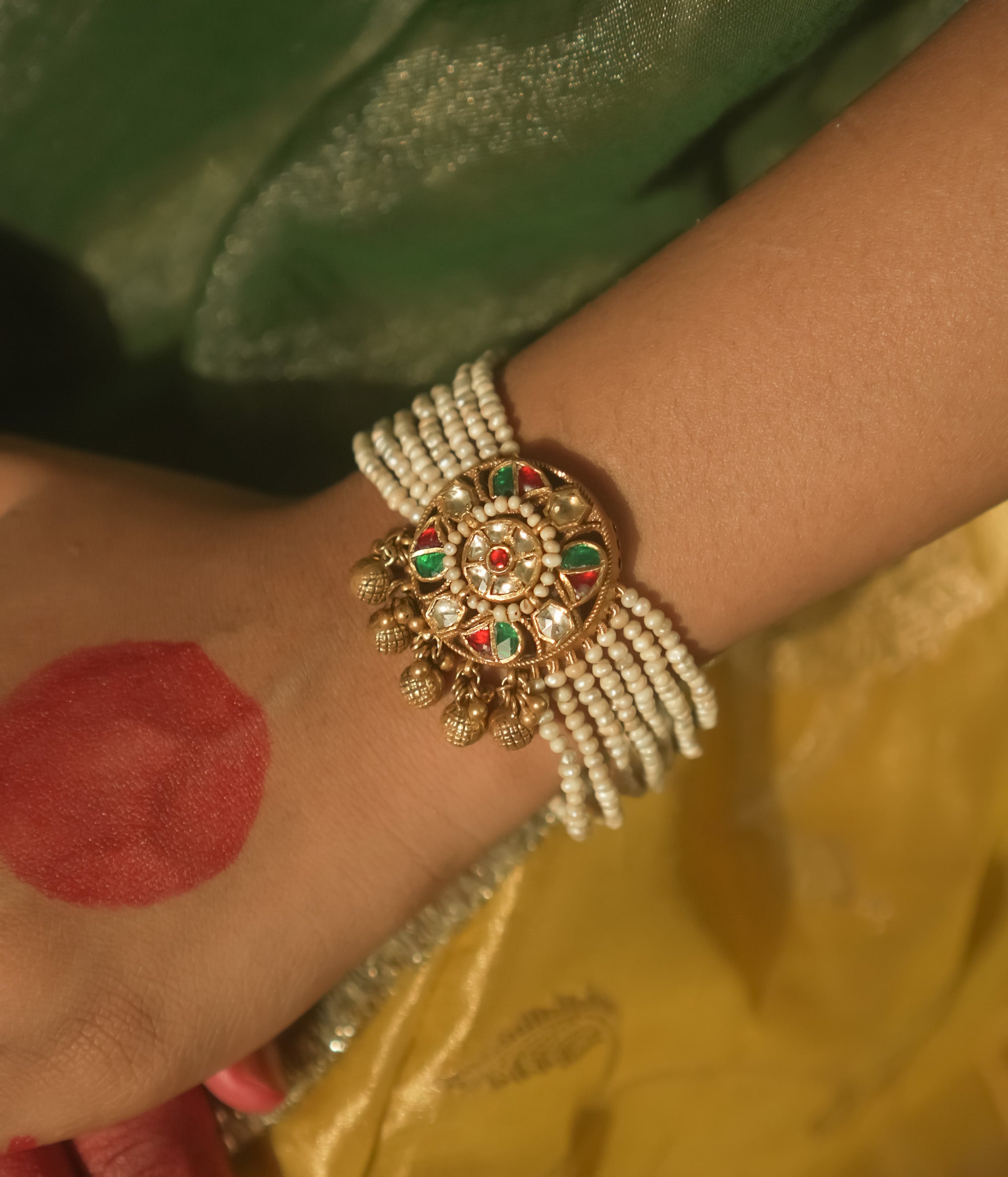 Bracelet with beaded pearls and a gold centerpiece studded with red and green Kundan.
