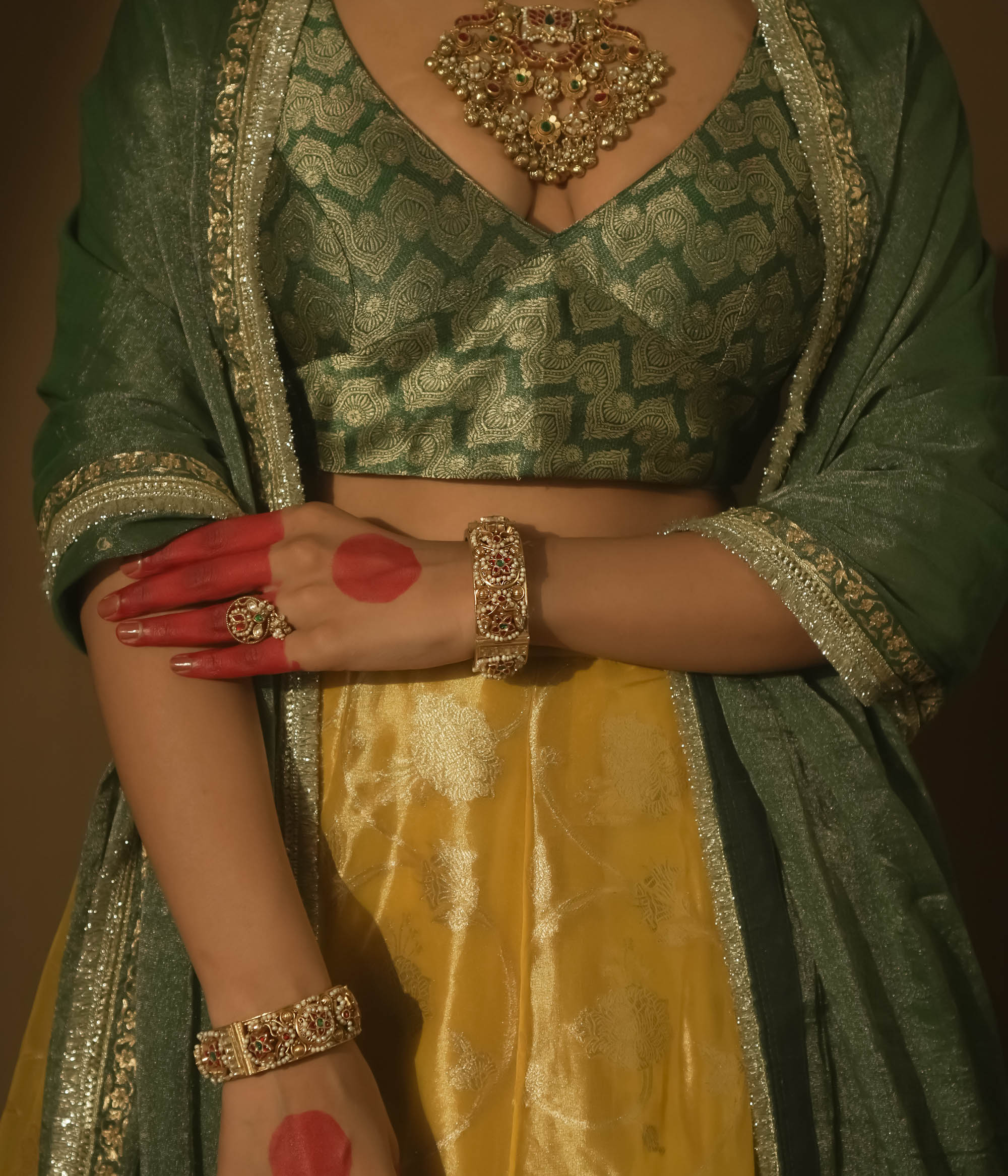 Gold-plated bangle with red and green Kundan gems and intricate patterns.
