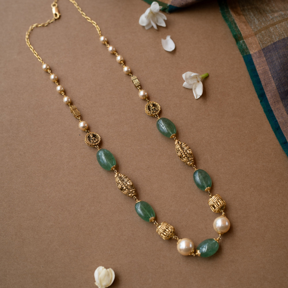 A layered chain necklace with a strand of green beads and a strand of pearls.