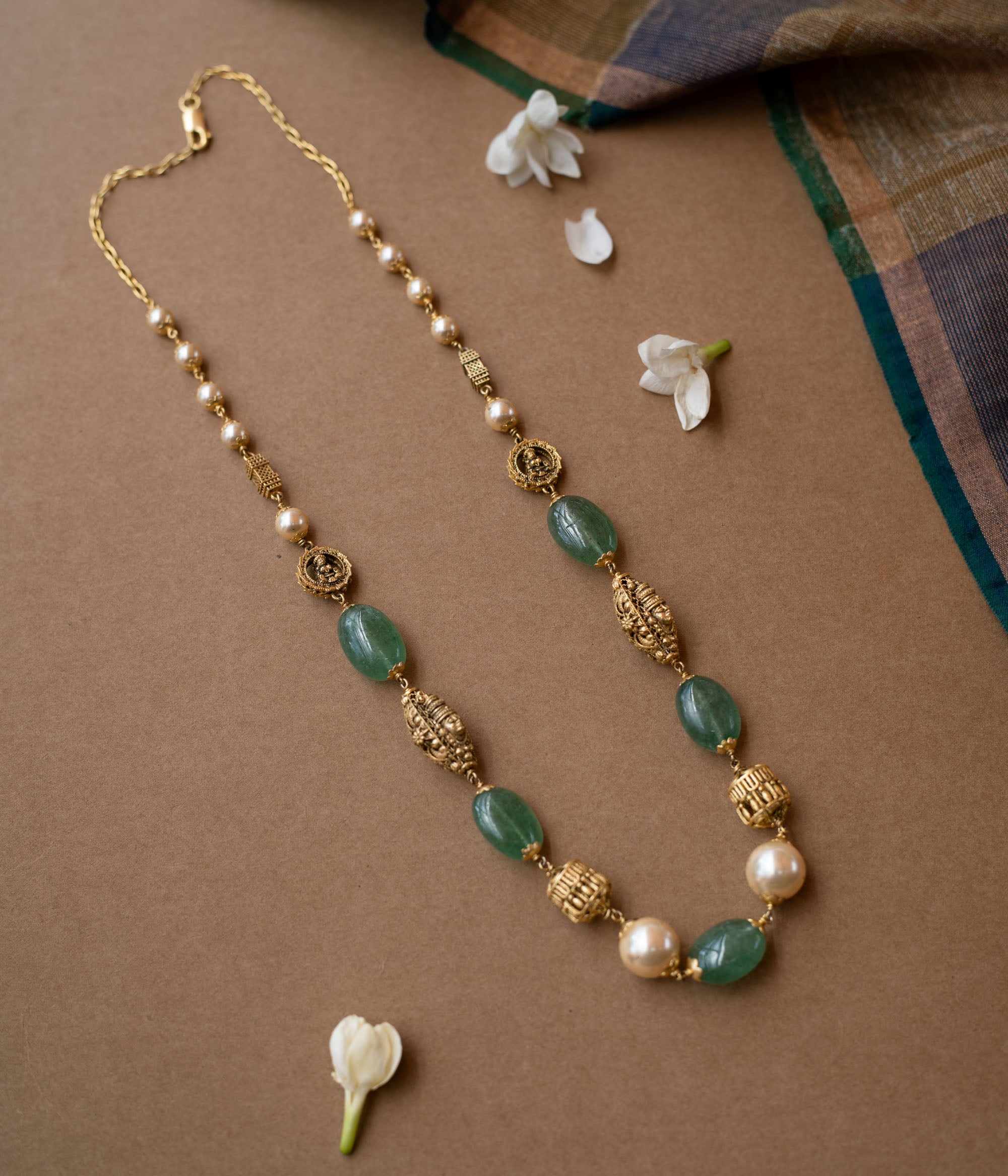 A layered chain necklace with a strand of green beads and a strand of pearls.