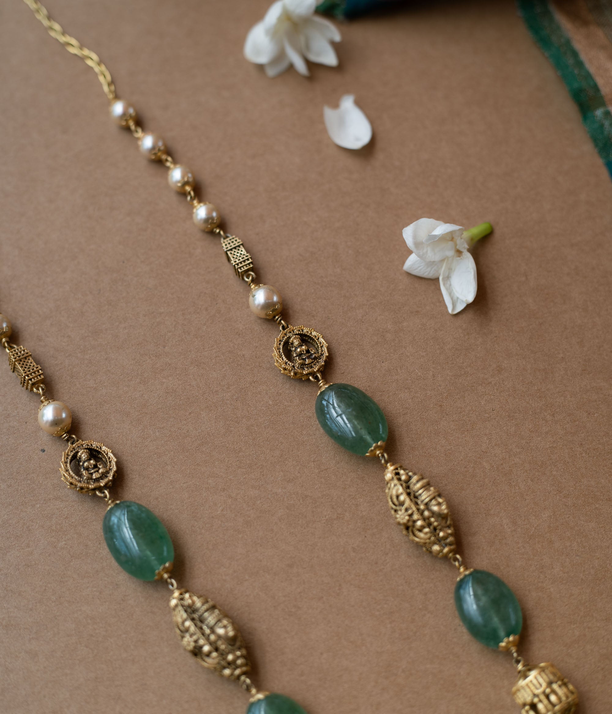 A layered chain necklace with a strand of green beads and a strand of pearls.