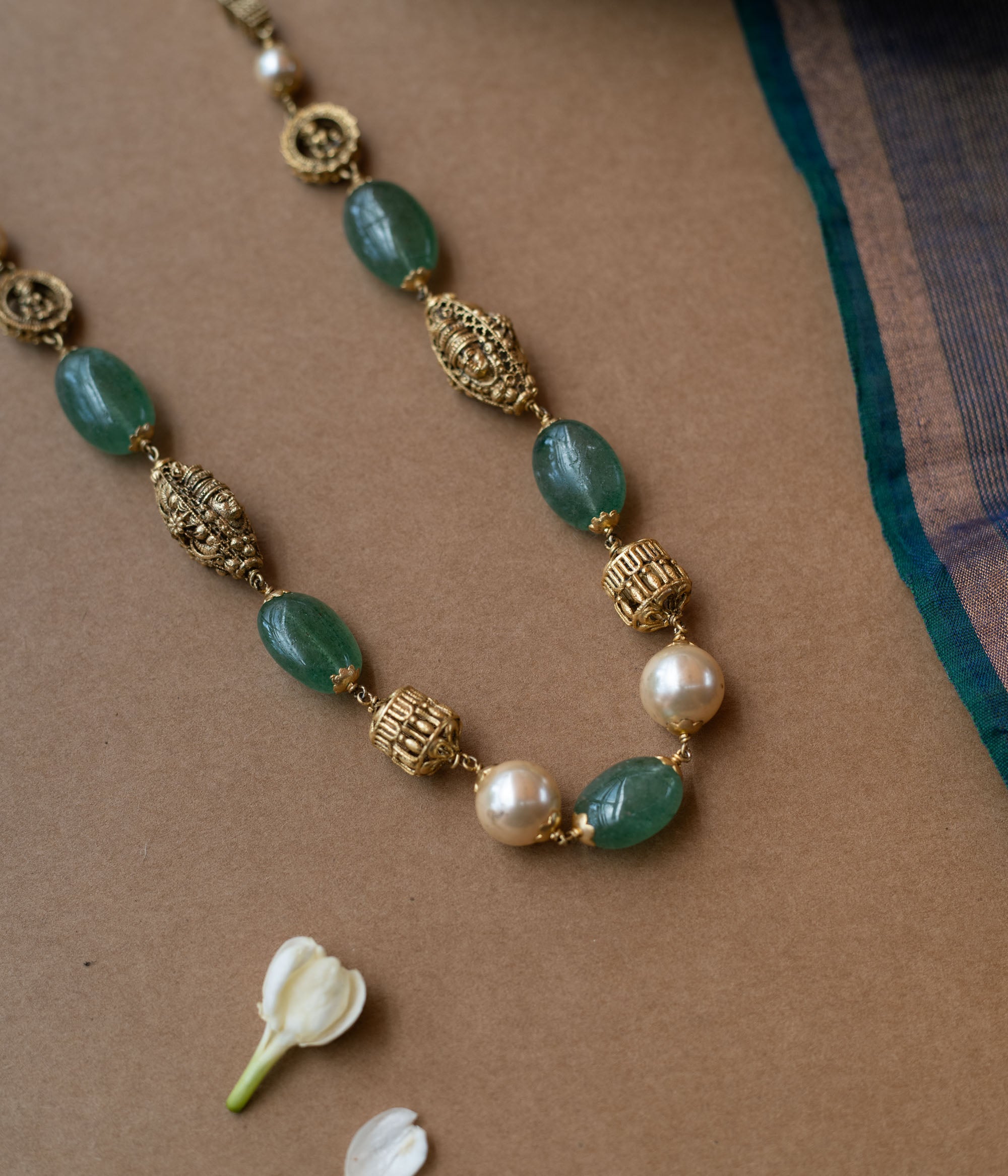 A layered chain necklace with a strand of green beads and a strand of pearls.