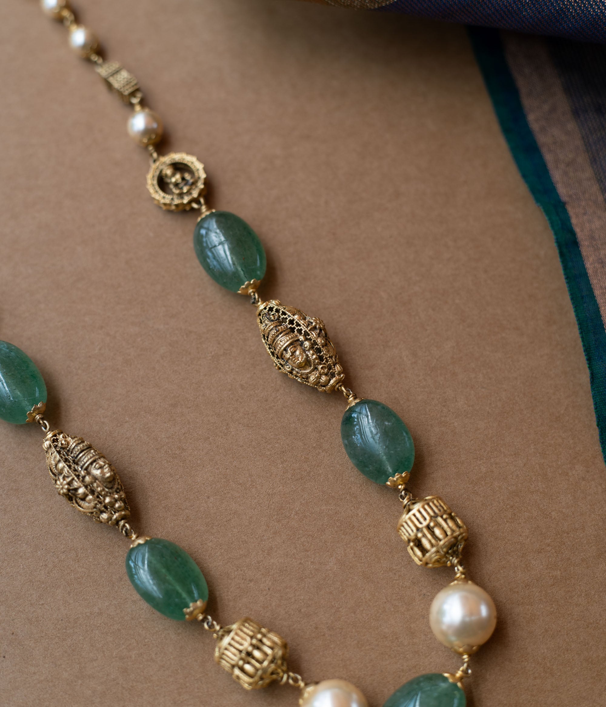 A layered chain necklace with a strand of green beads and a strand of pearls.