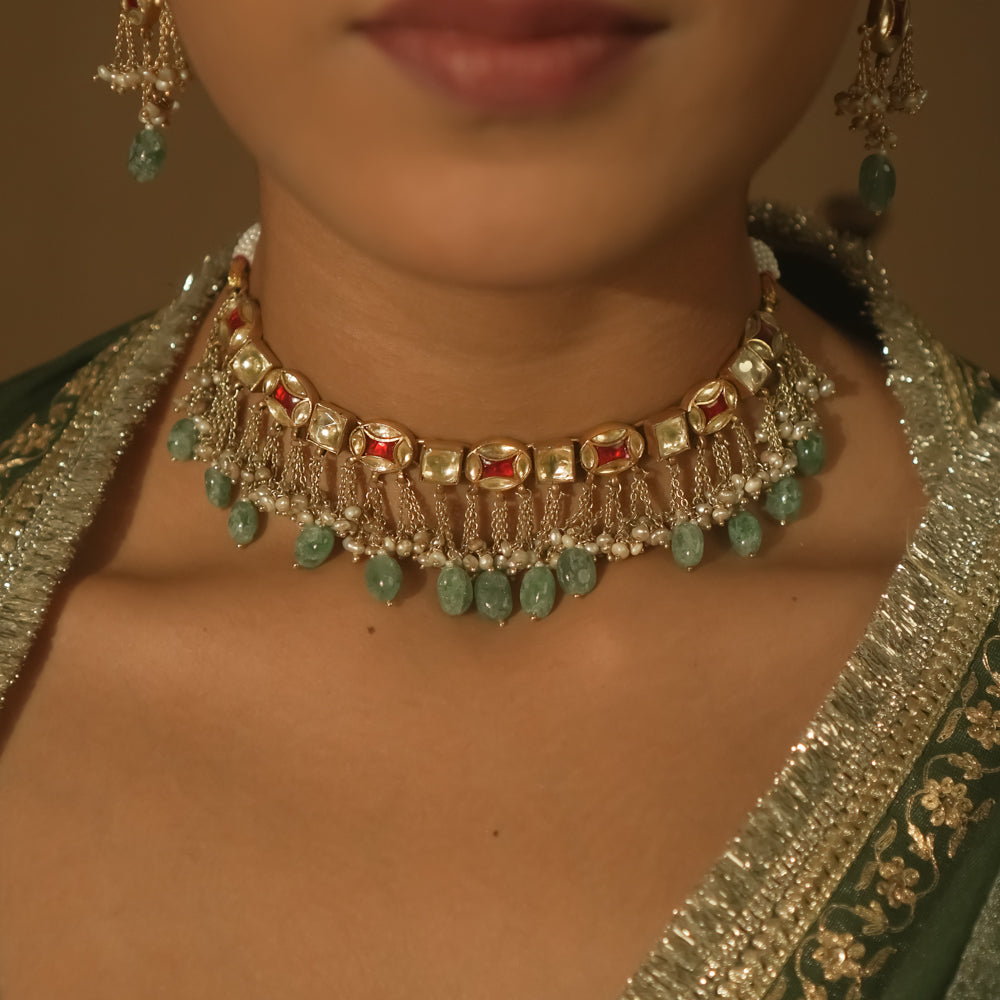 Gold necklace with tassels, clear stones, and teardrop emeralds.