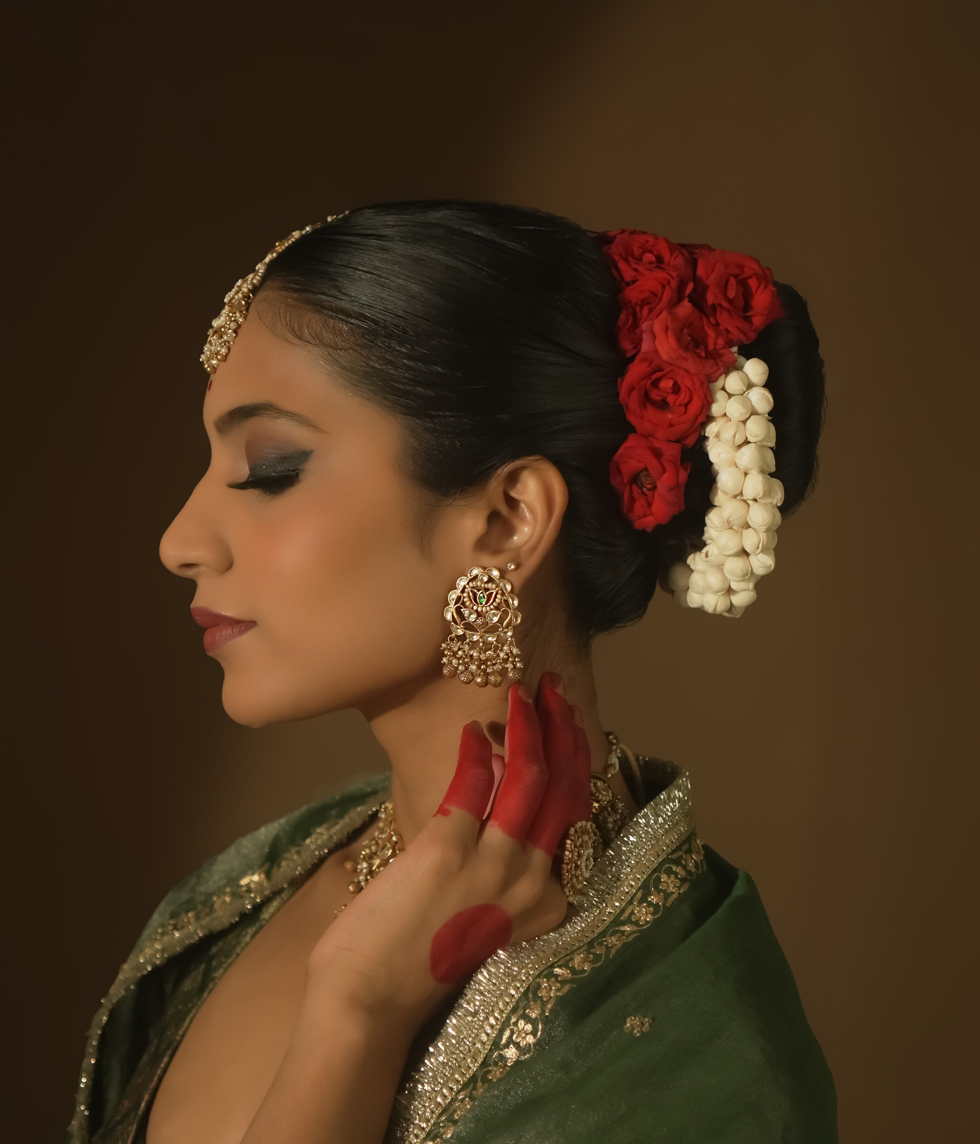 Gold-plated silver earrings with beaded tassels and a central medallion with green Kundan stones.