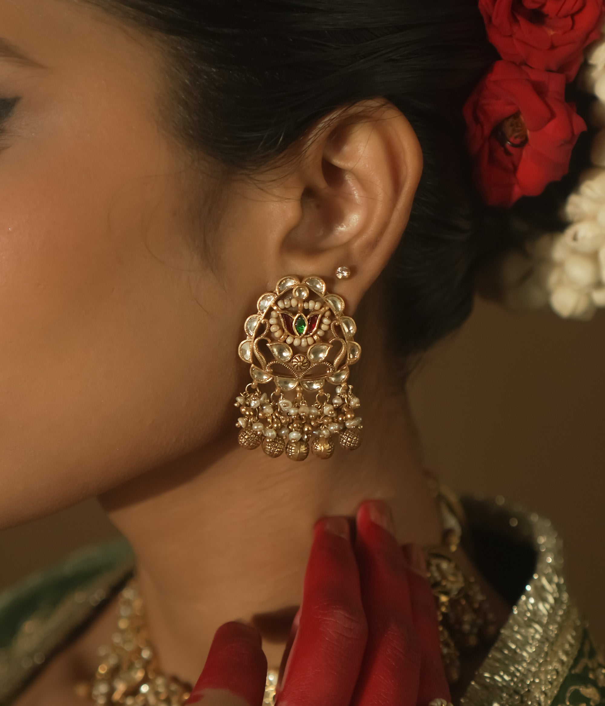 Gold-plated silver earrings with beaded tassels and a central medallion with green Kundan stones.