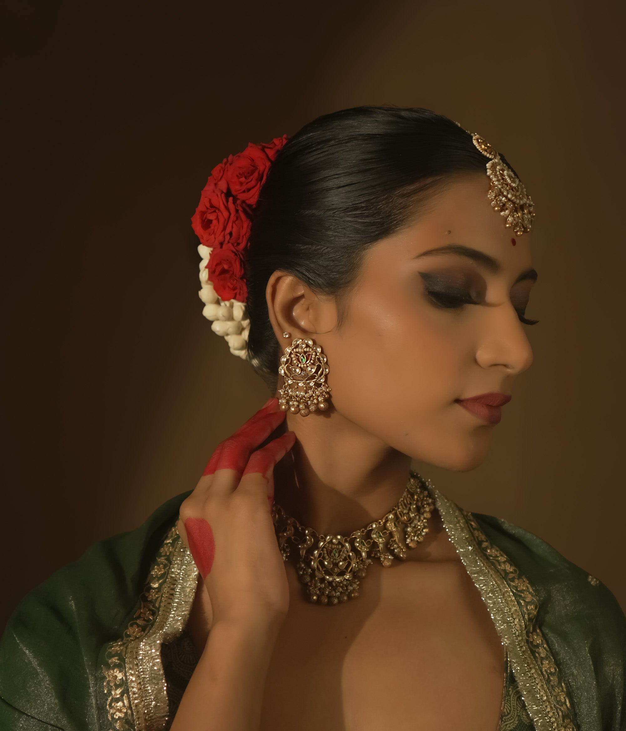 Gold-plated silver earrings with beaded tassels and a central medallion with green Kundan stones.