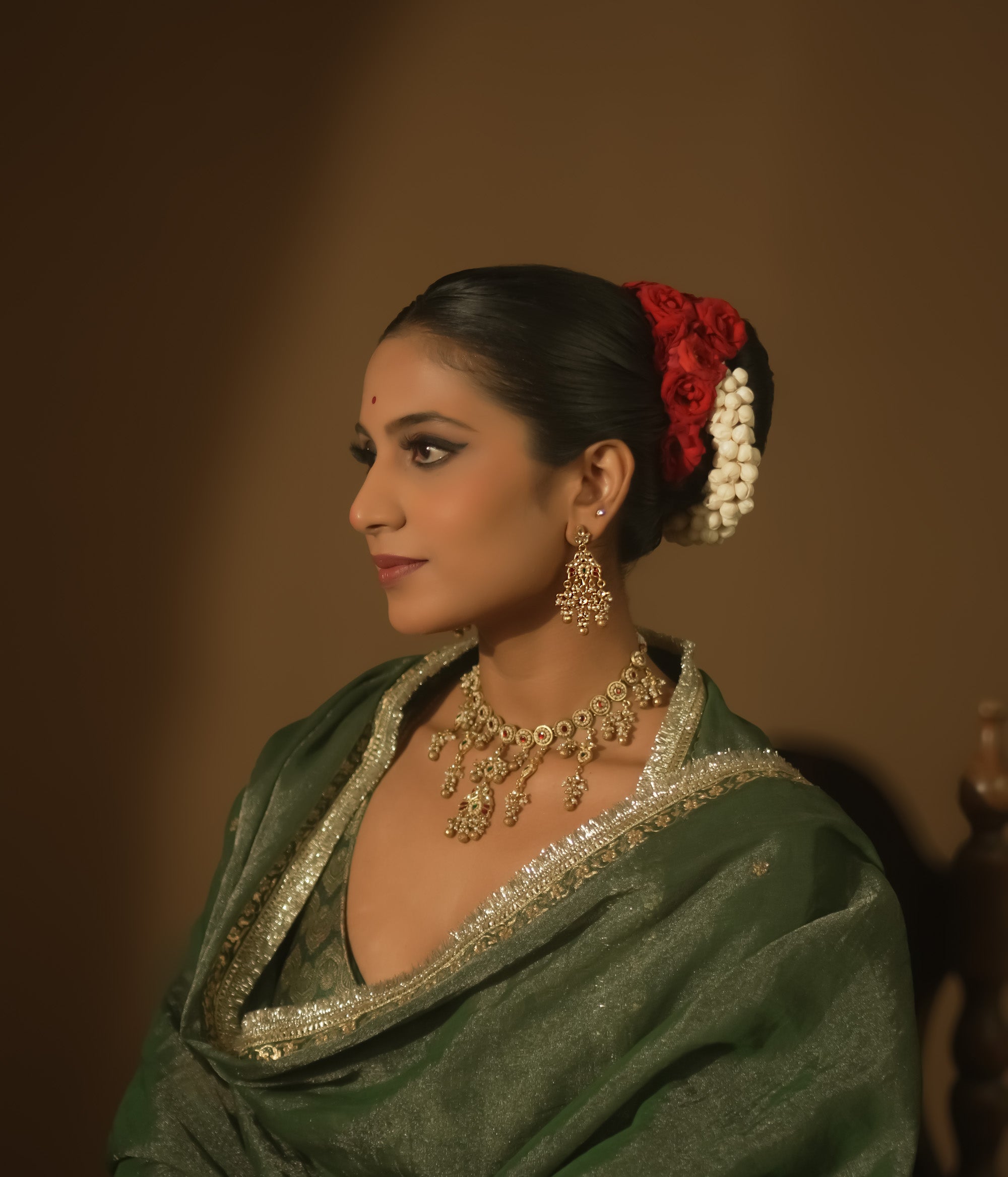 Gold-plated silver earrings with tasseled Kundan clusters, red gems, and pearls.