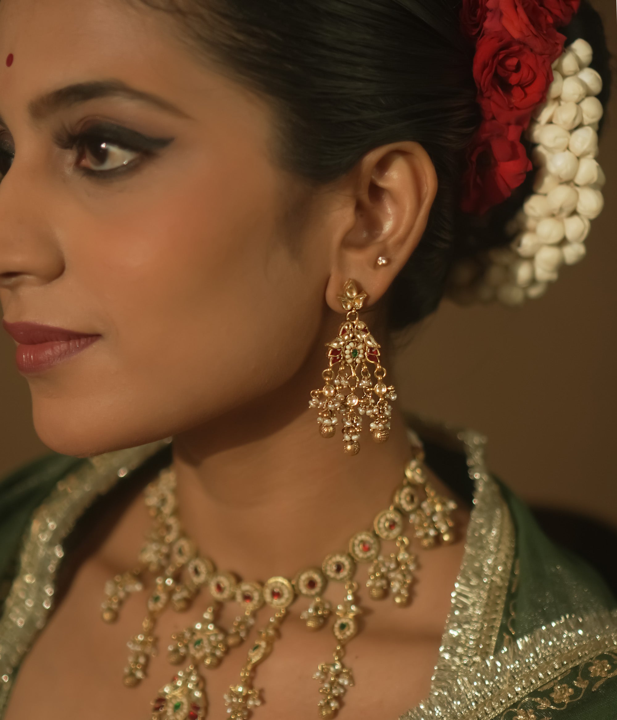 Gold-plated silver earrings with tasseled Kundan clusters, red gems, and pearls.